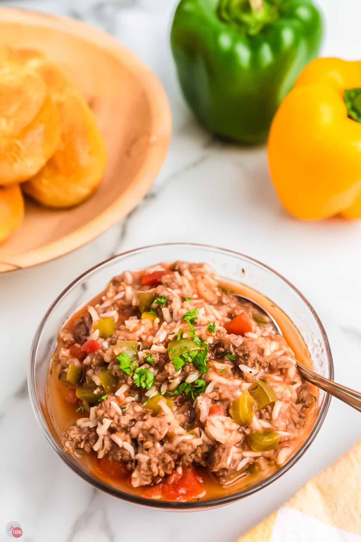bowl of stuffed bell pepper soup with plate of bread behind it