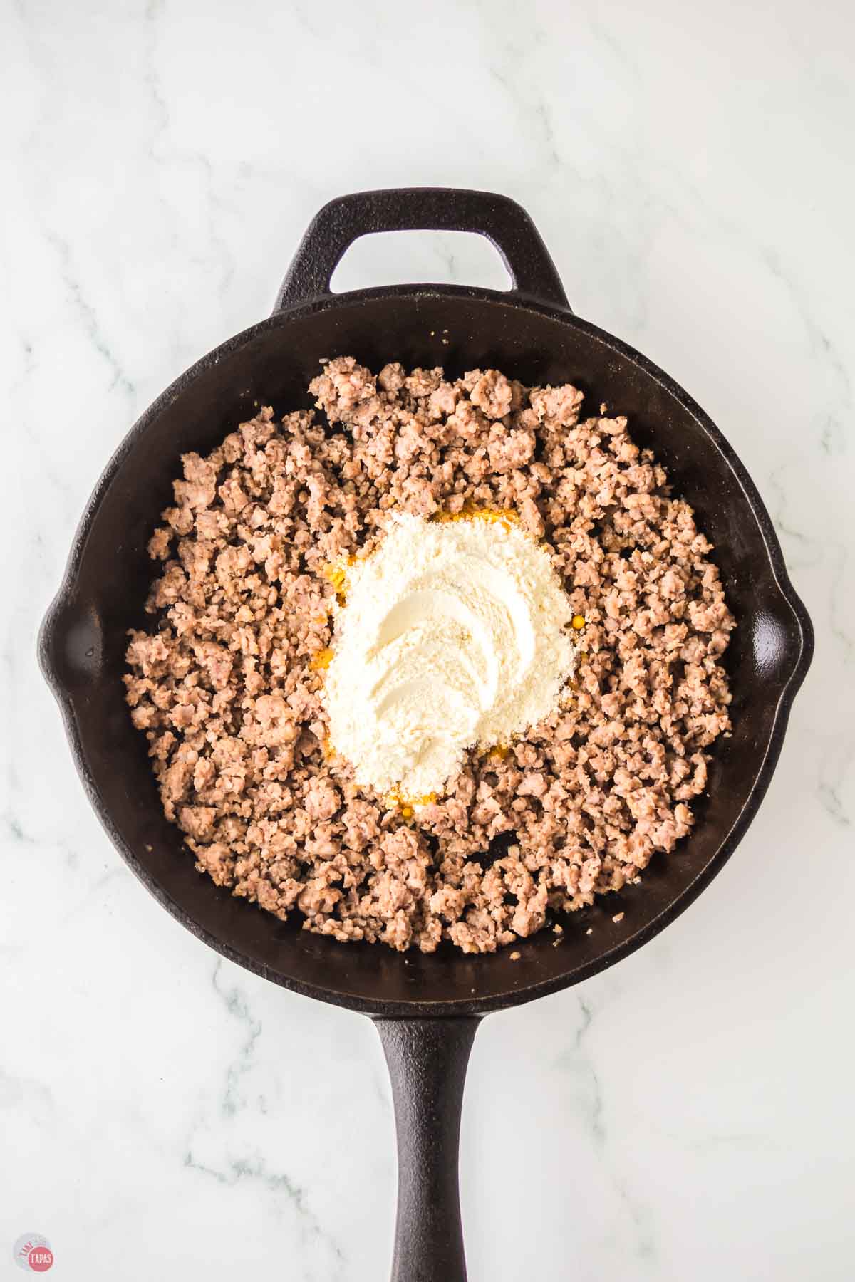 black skillet with cooked pork sausage and flour