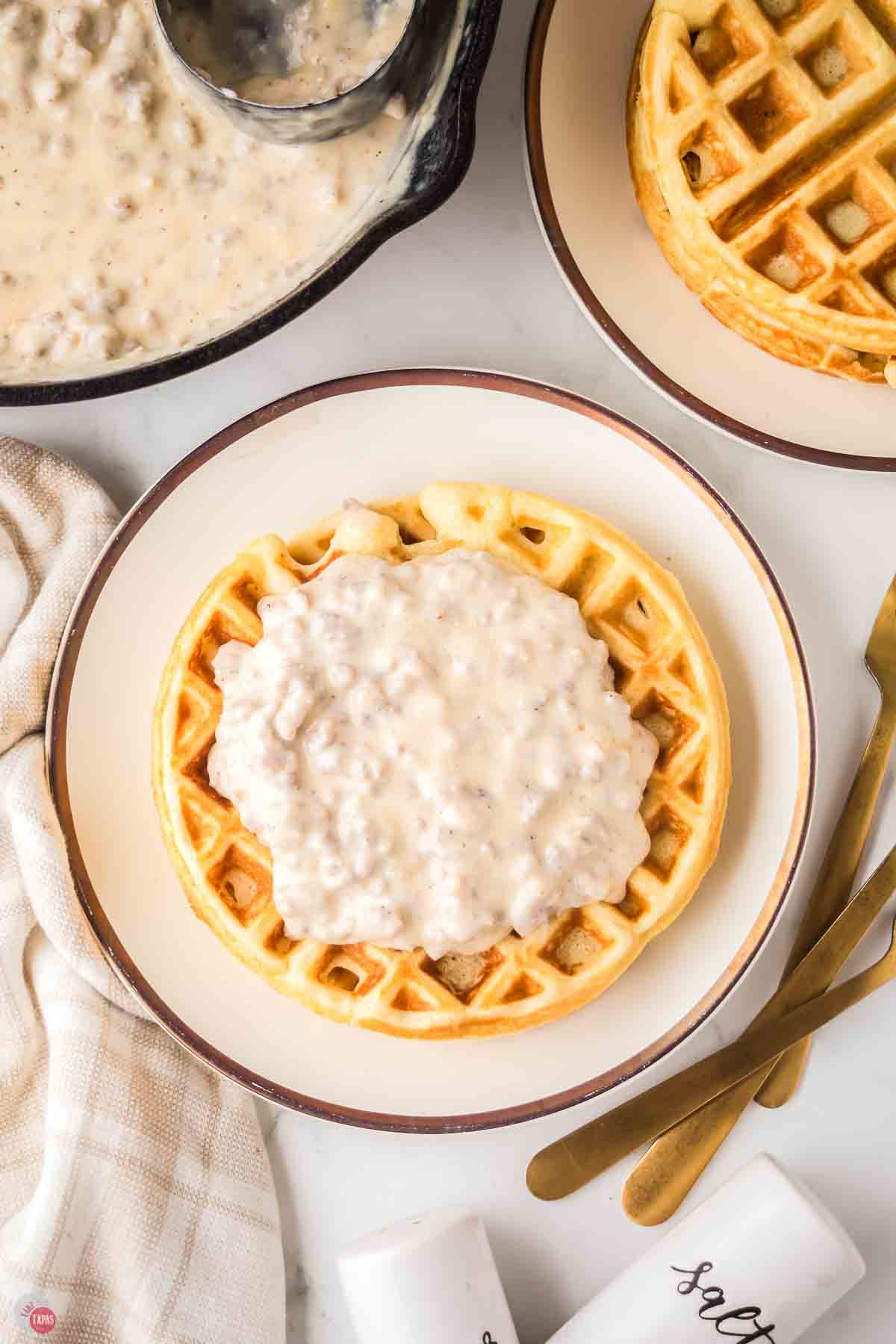 plate of round waffle topped with sausage gravy