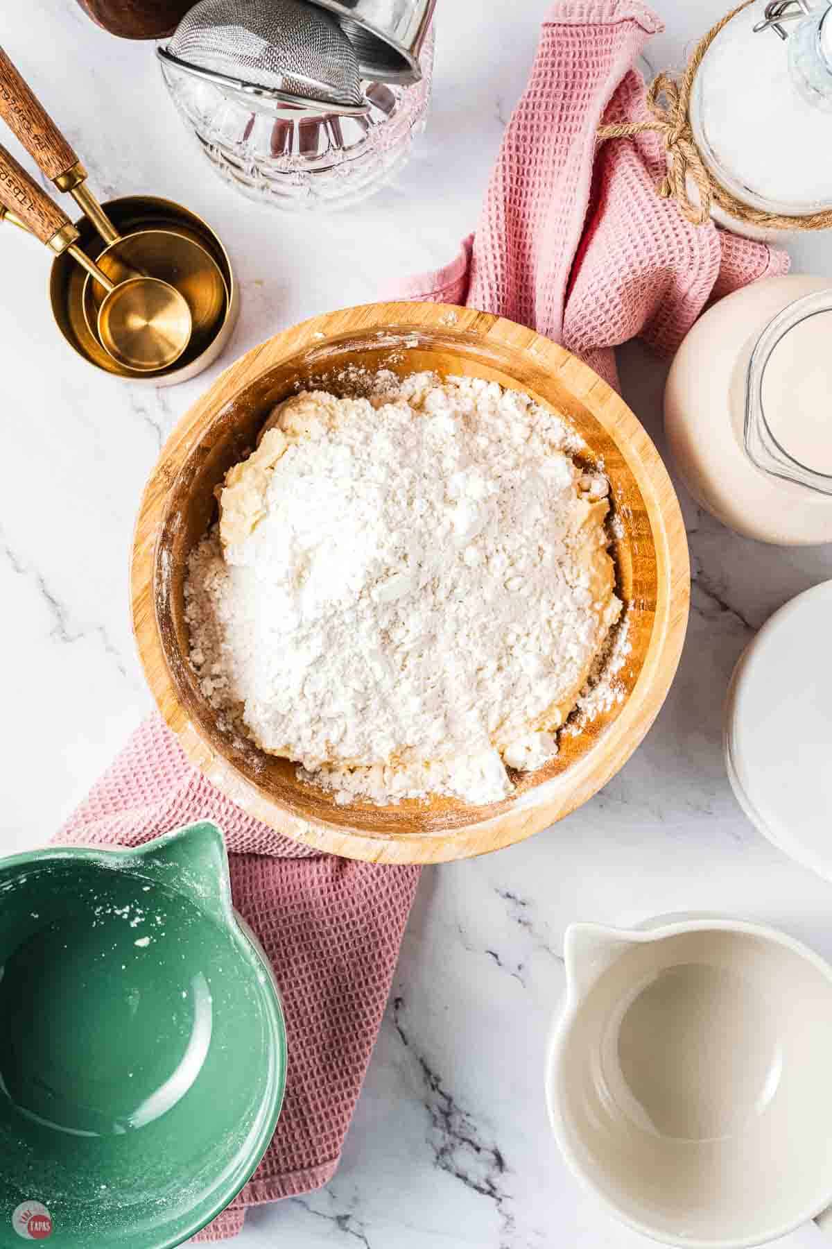 flour on top of creamed butter in a wood bowl