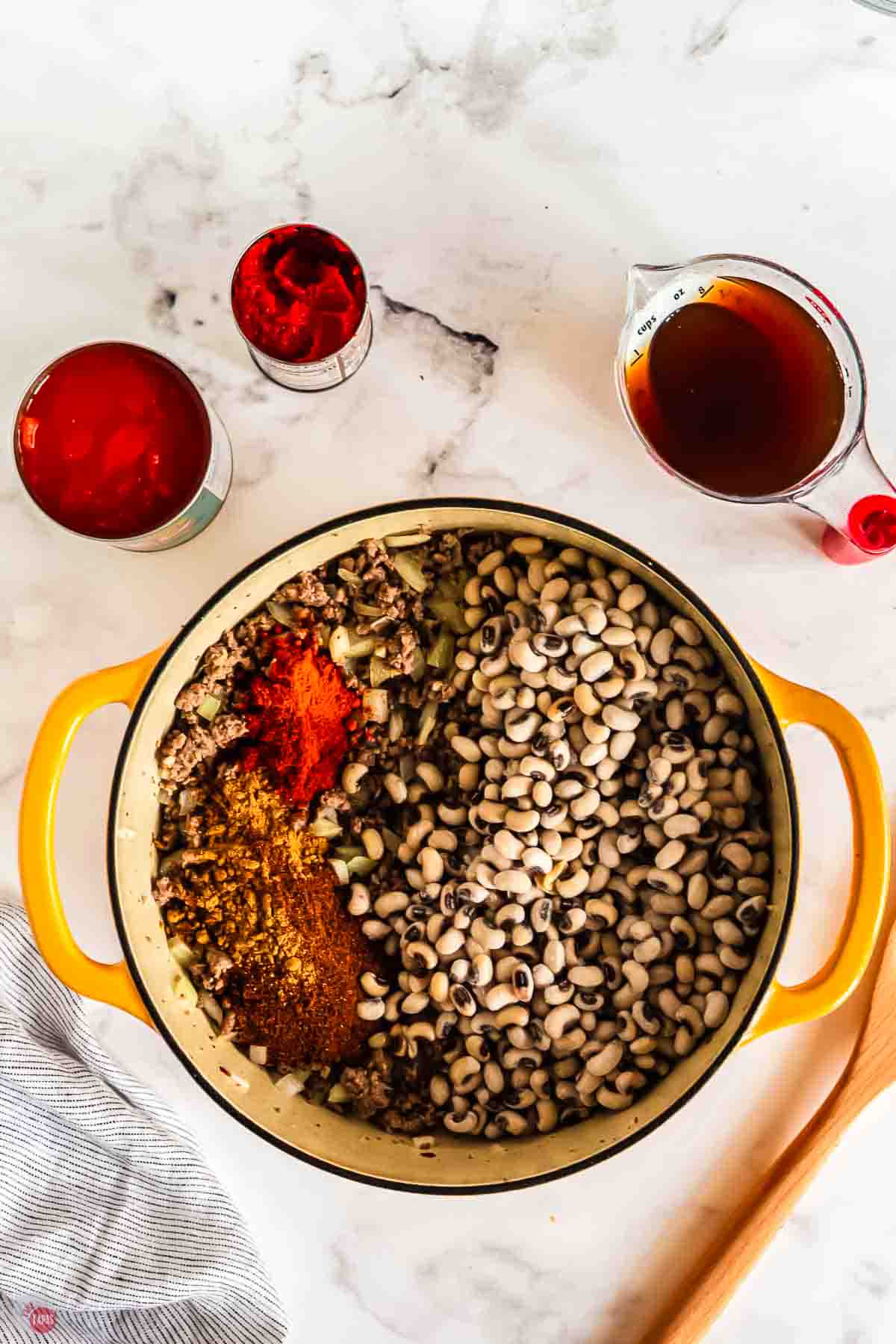 cooked ground beef in a yellow pot with two spices added on top
