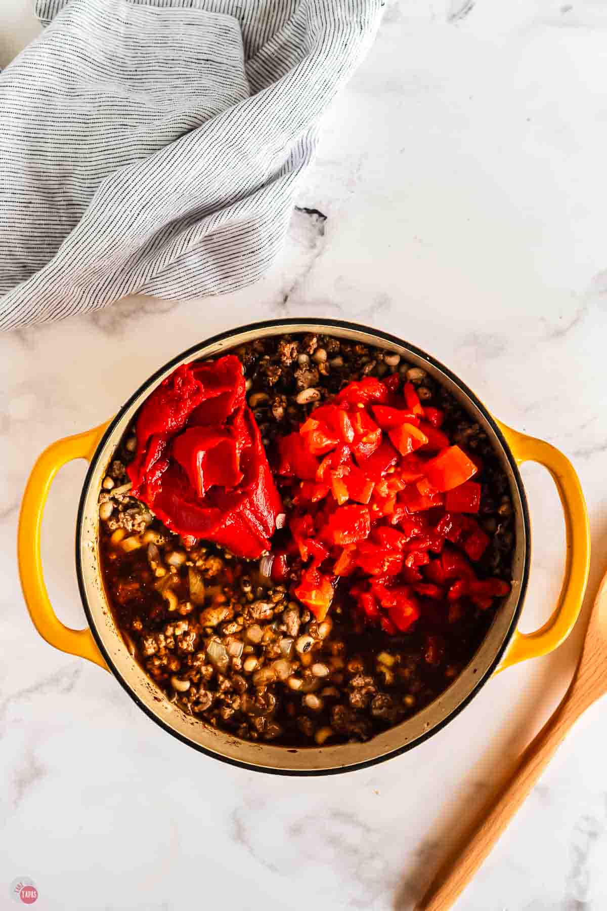 yellow pot with meat and diced tomatoes in it