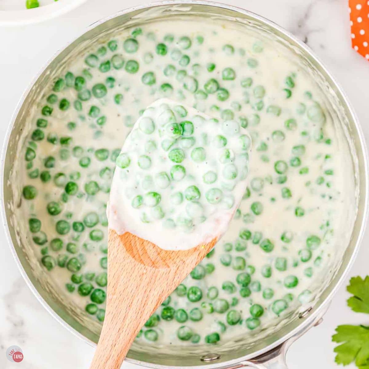 skillet of creamed peas with a wood spoon