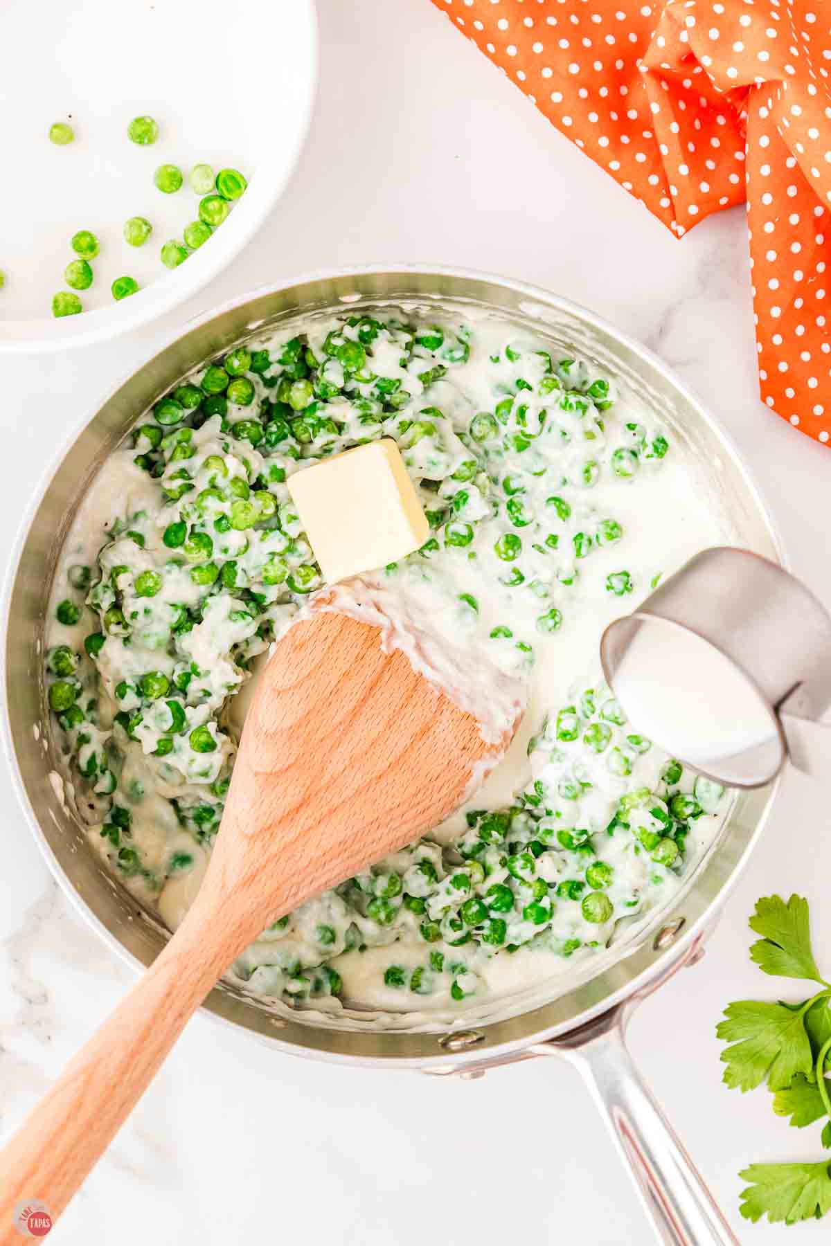 butter and cream being added to a skillet of creamy peas