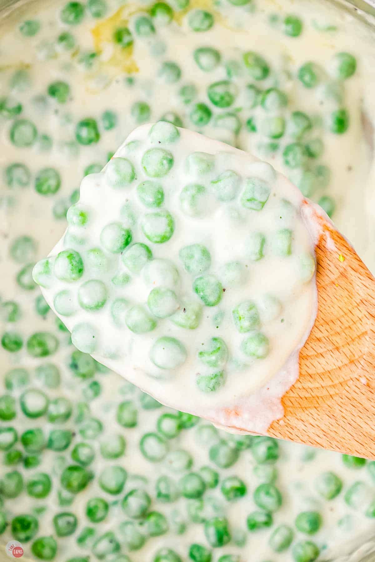 close up of creamed peas on a wood spoon