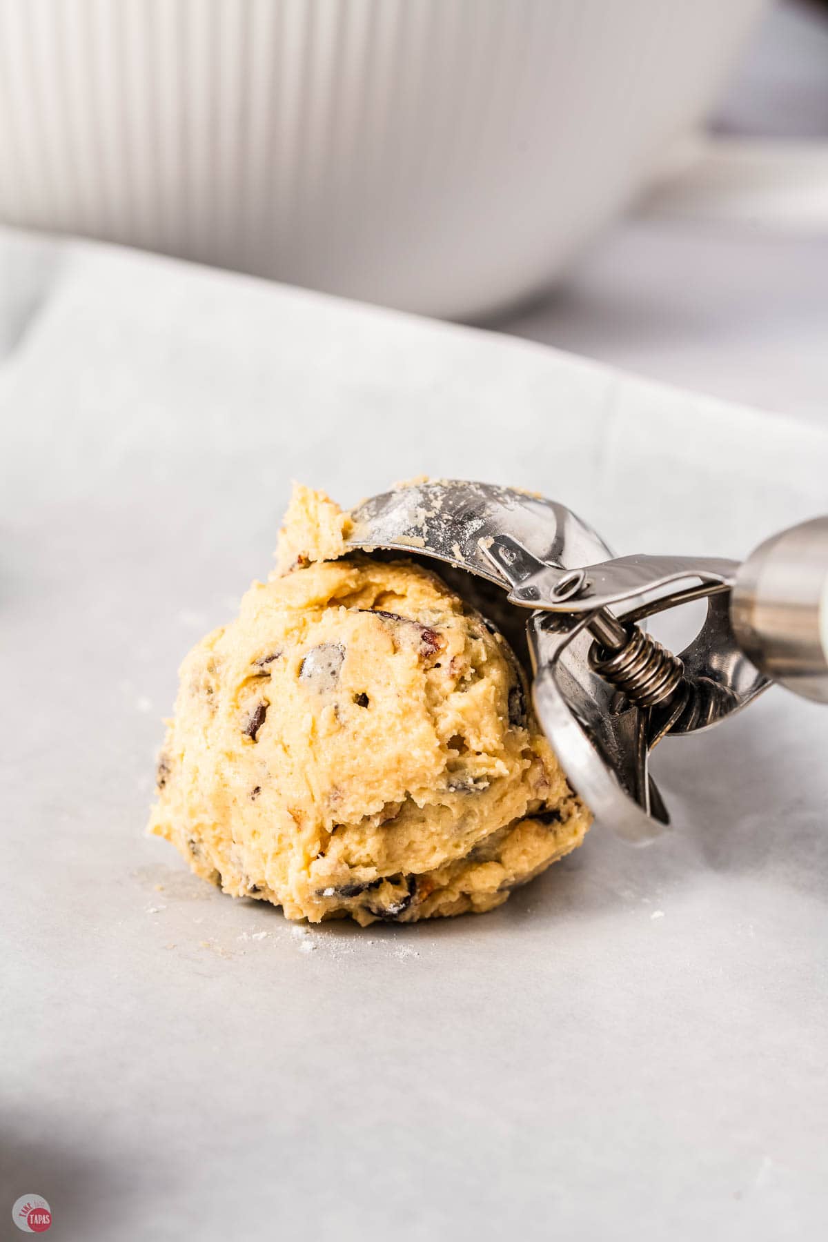 ice cream scoop putting cookie dough on a piece of parchment paper