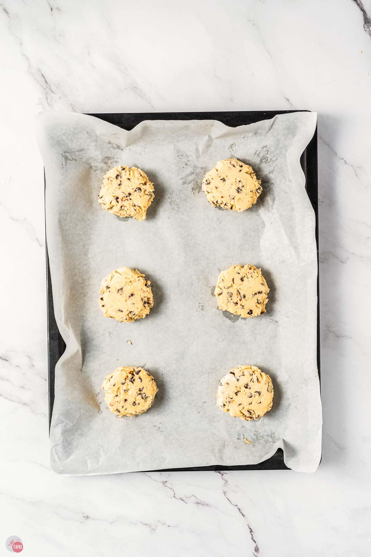 slightly flattened cookie dough on parchment paper