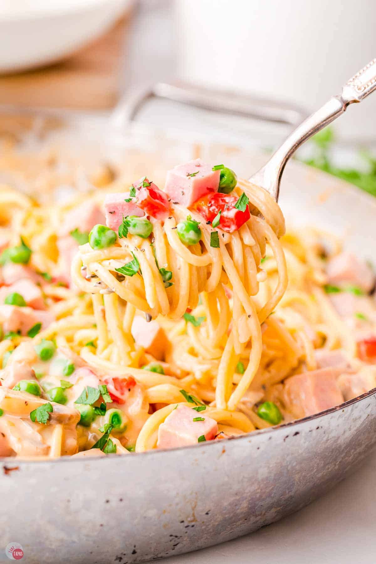 fork with ham, peas, and spaghetti on it