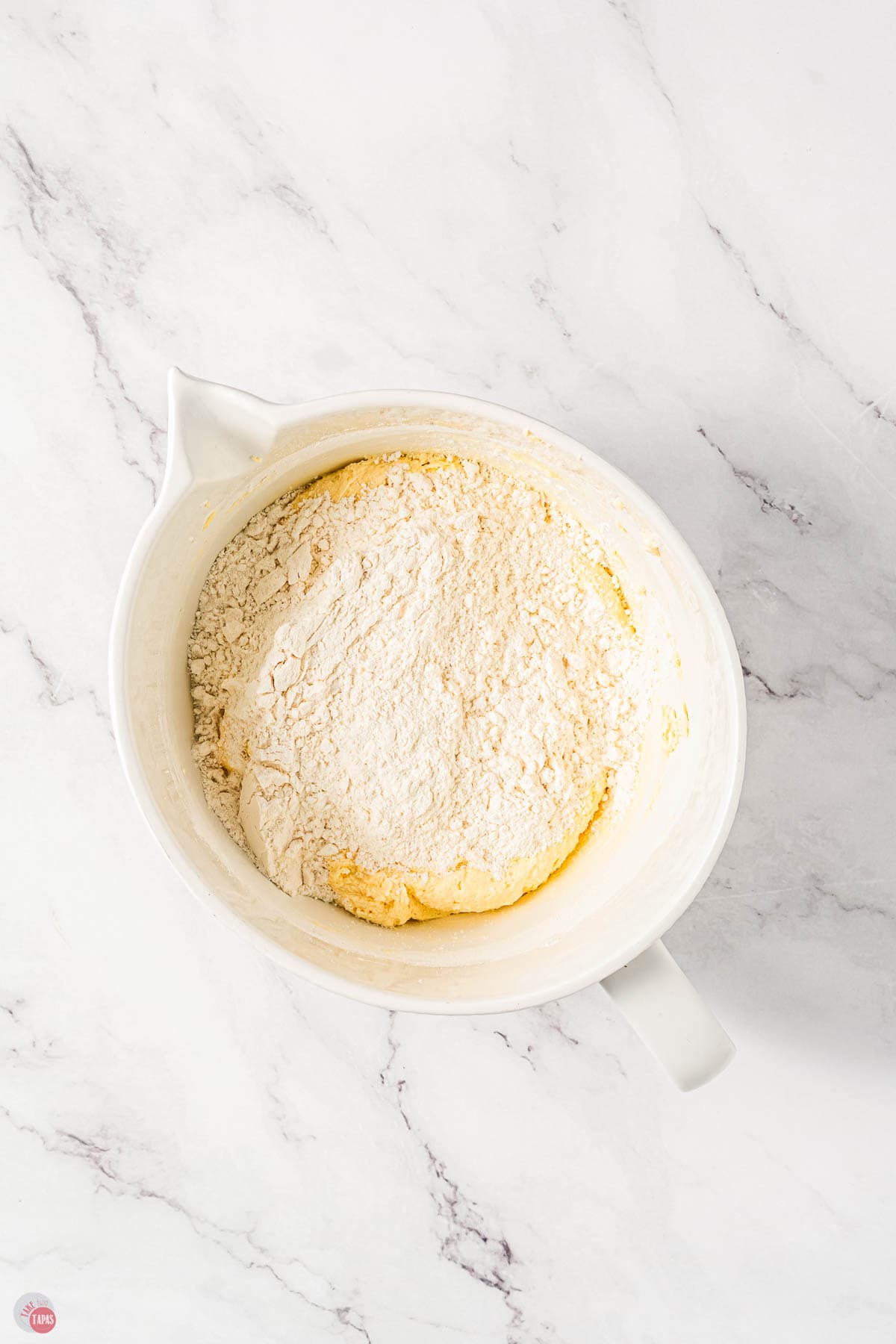 flour on top of butter mixture in a white bowl