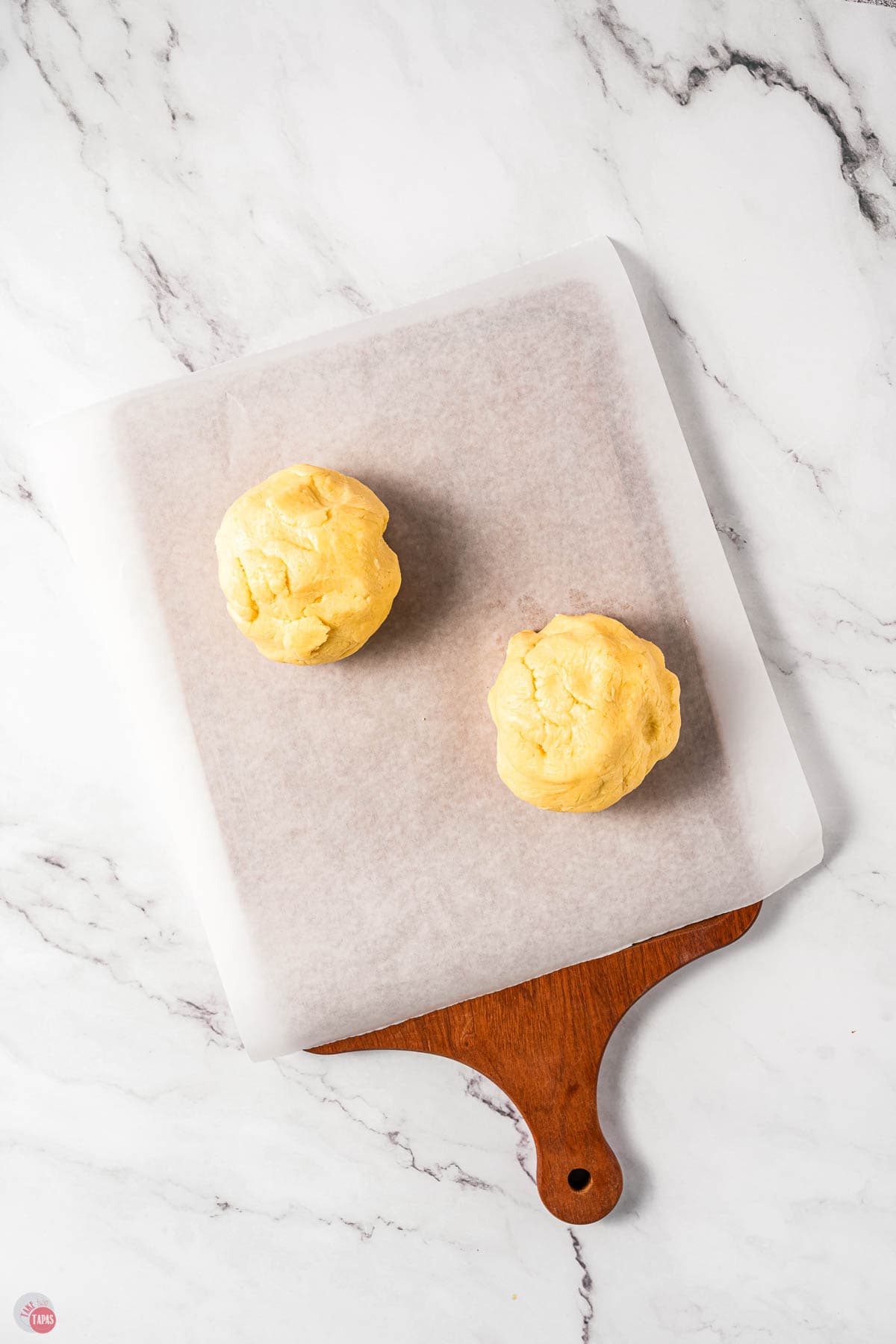 two balls of cookie dough on a cutting board with parchment paper