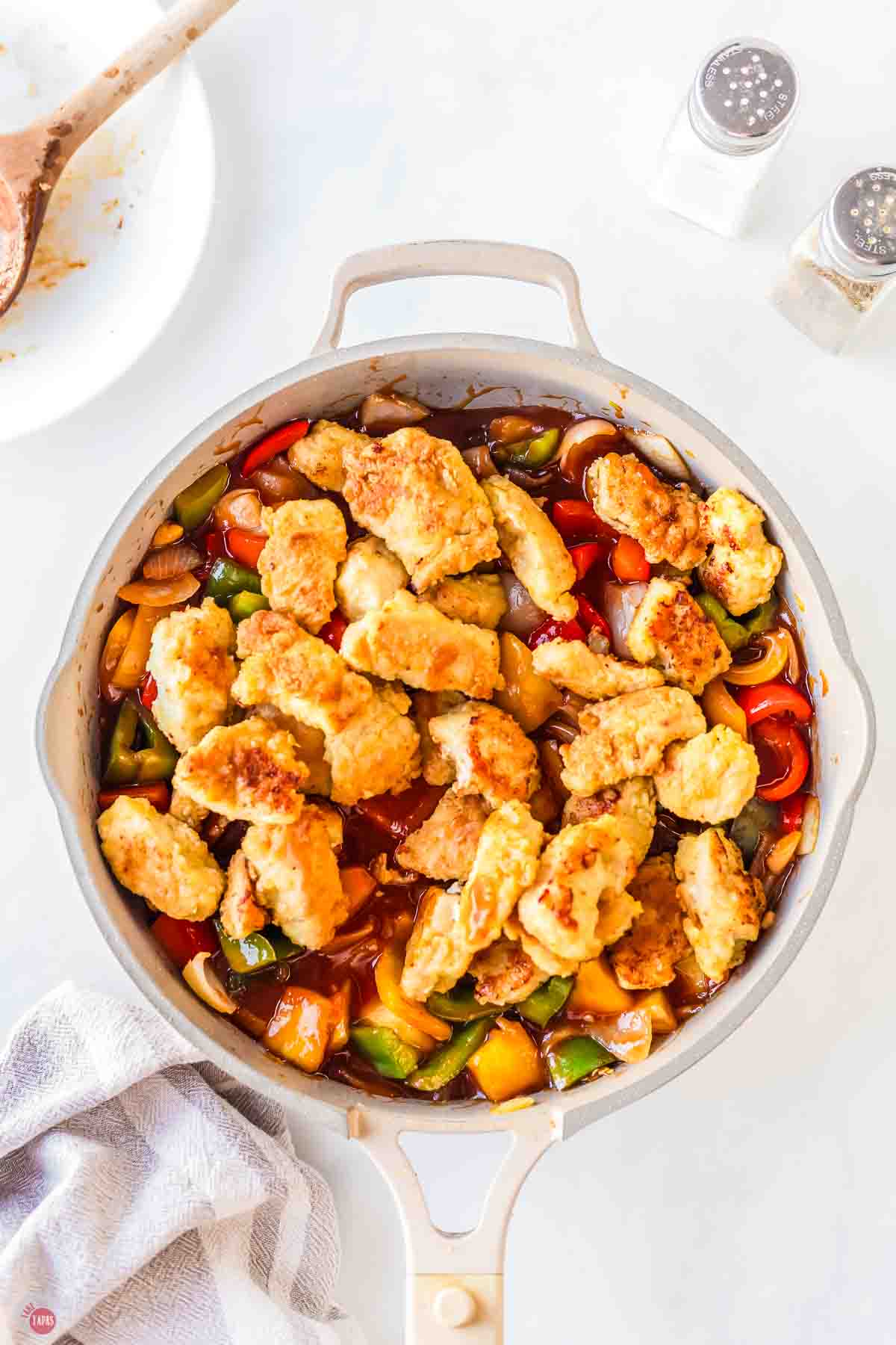 chicken tenders in a skillet with sauce and vegetables