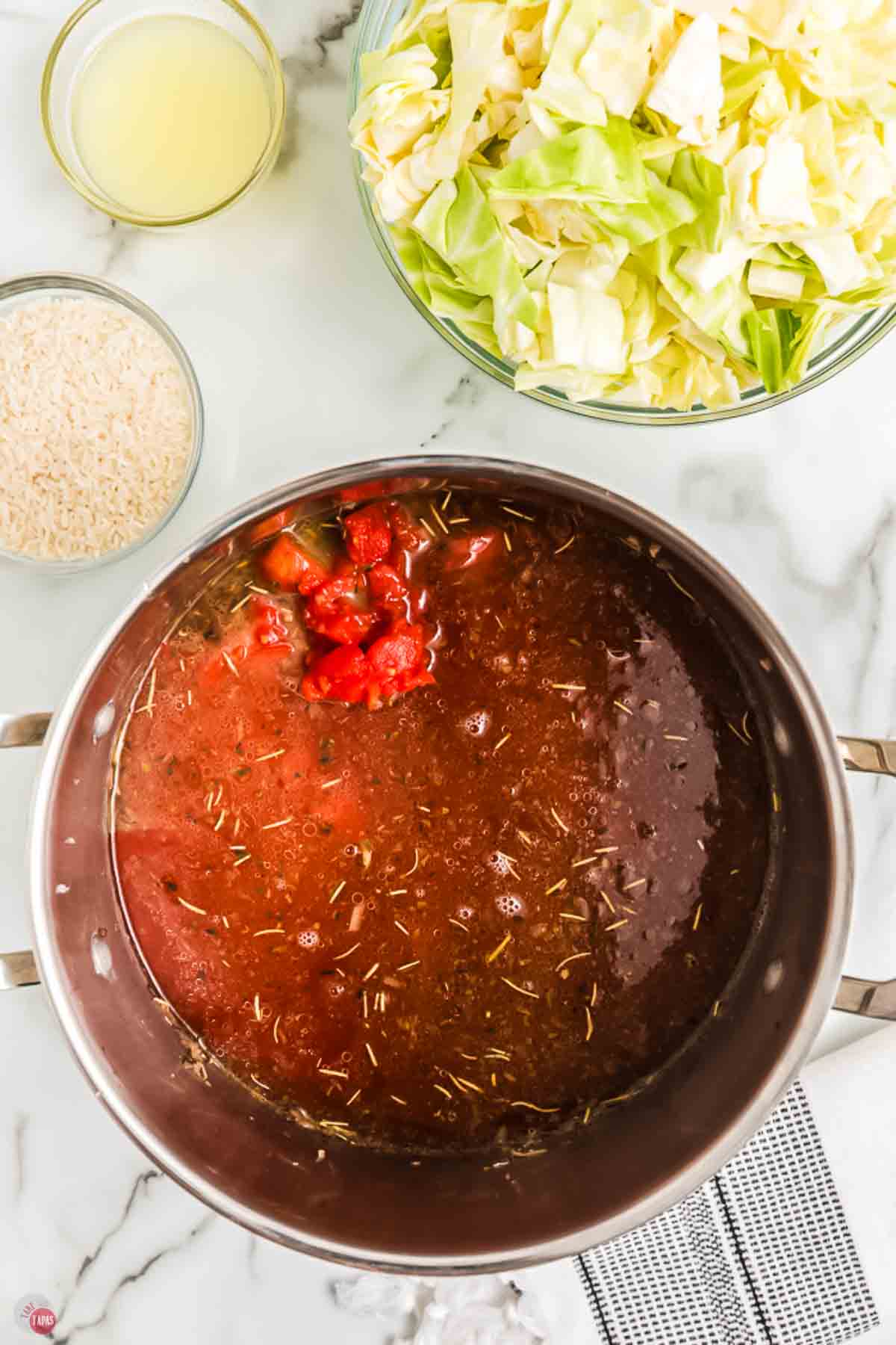 pot of soup with tomatoes next to a bowl of chopped cabbage