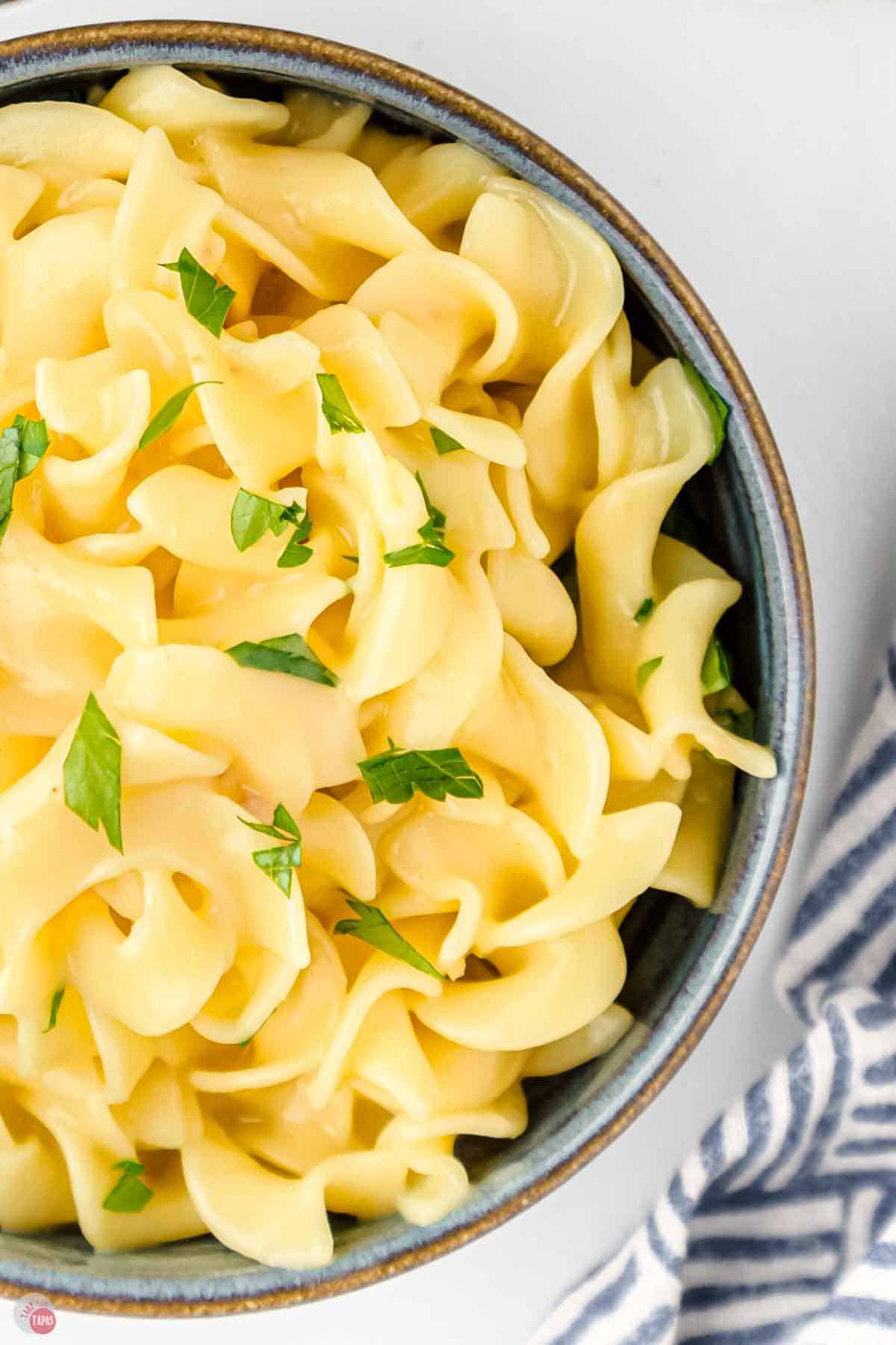 close up picture of egg noodles in a black bowl with parsley on top