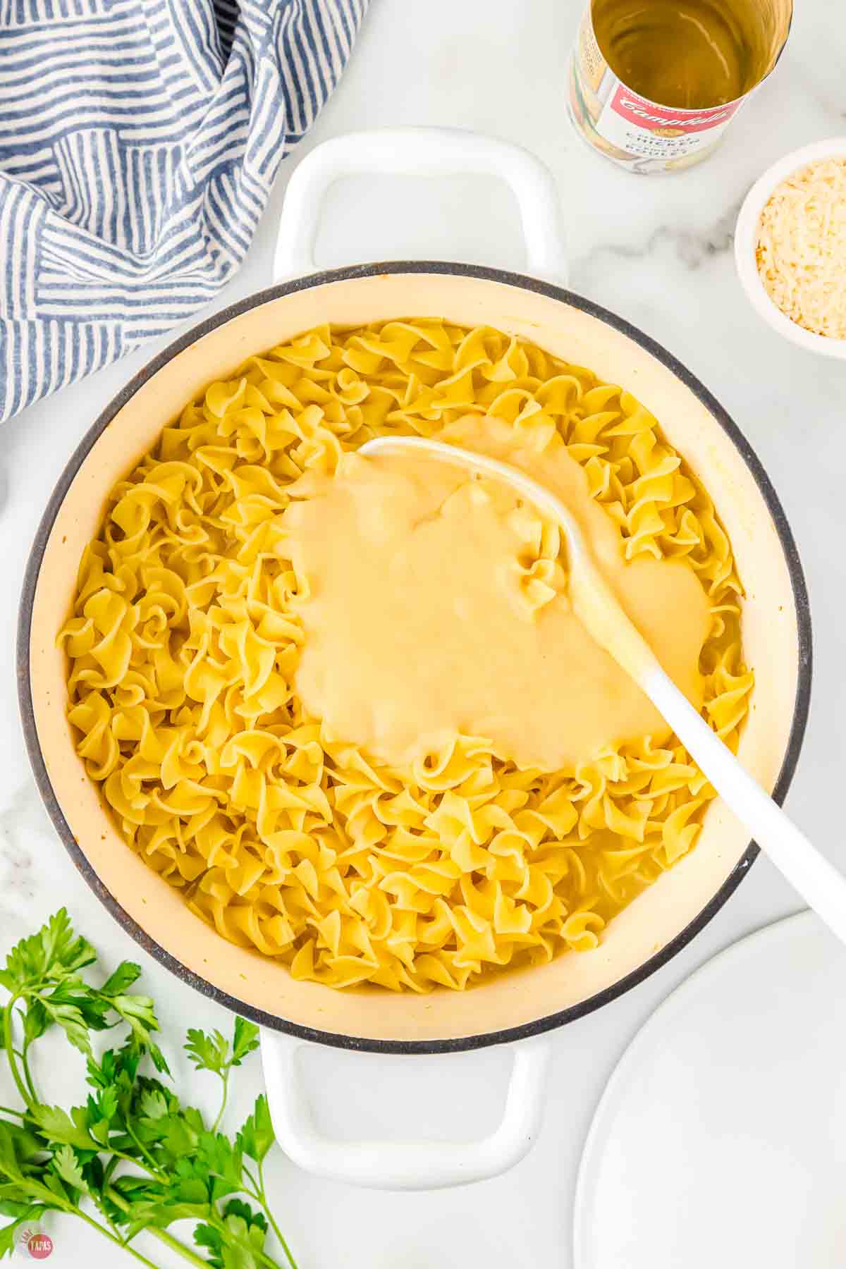cooked egg noodles in a pot with a spoon and sauce