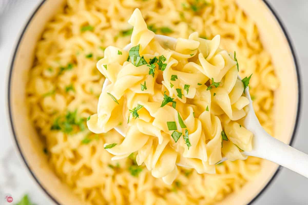 close up of cooked cafeteria noodles on a white serving spoon