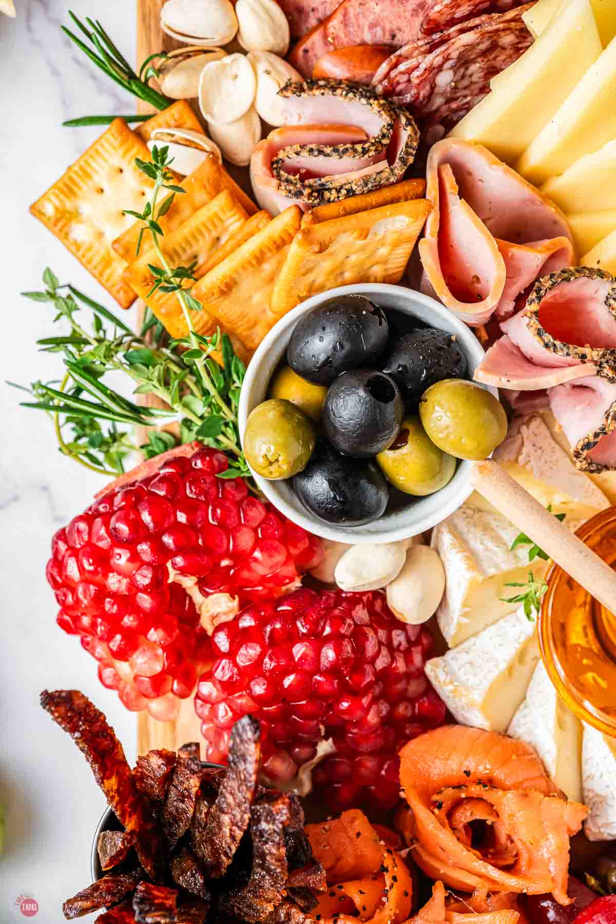 close up of bowl of olives and a pomegranate next to it