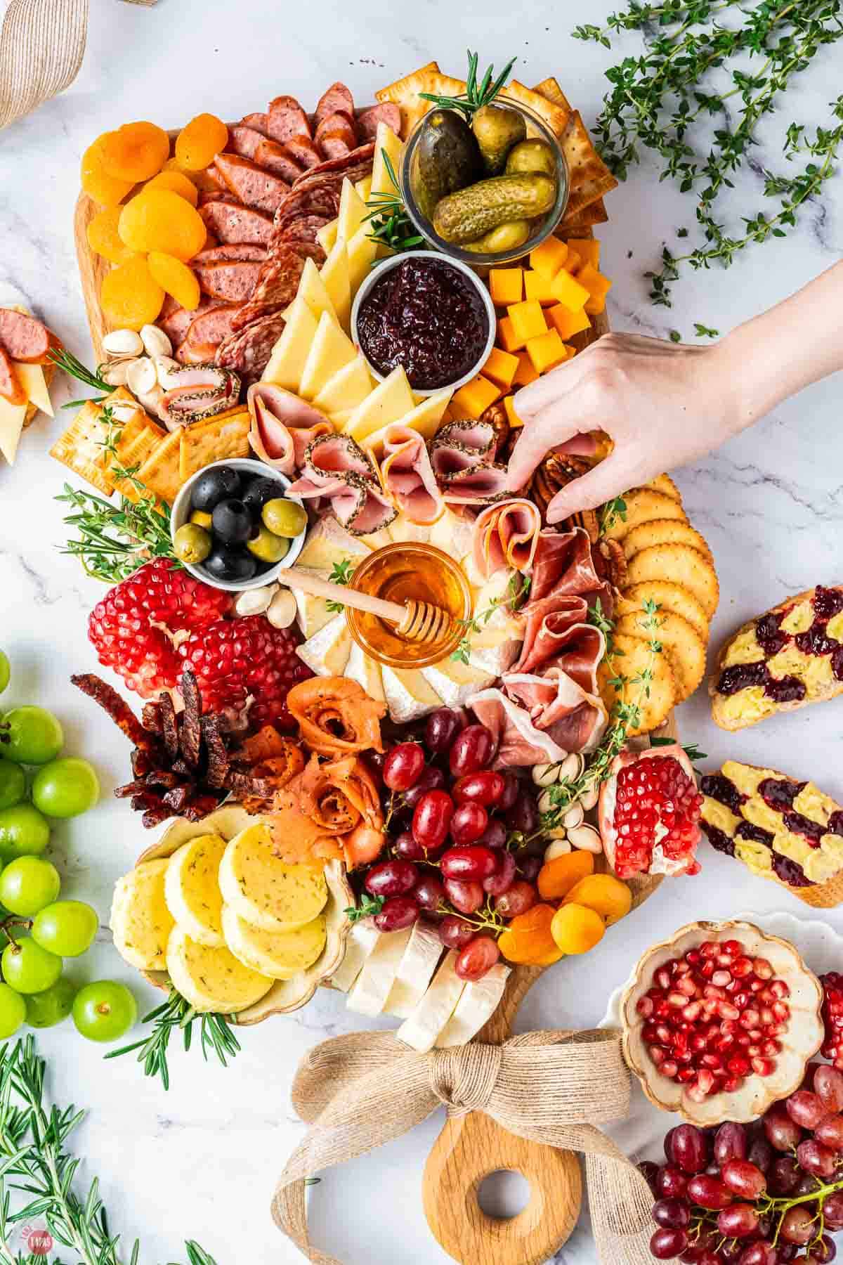 hand grabbing salami off a charcuterie board