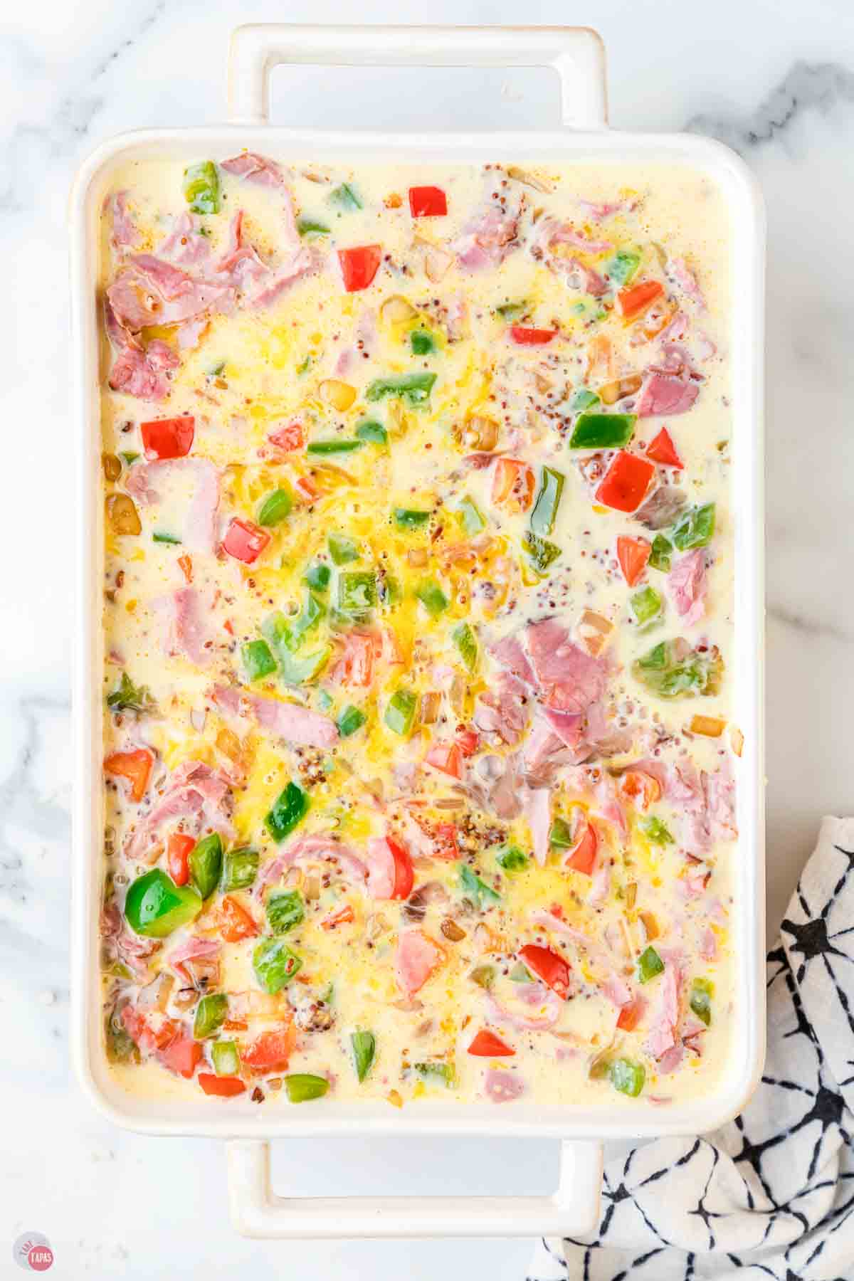 egg mixture with bell peppers in a white casserole dish