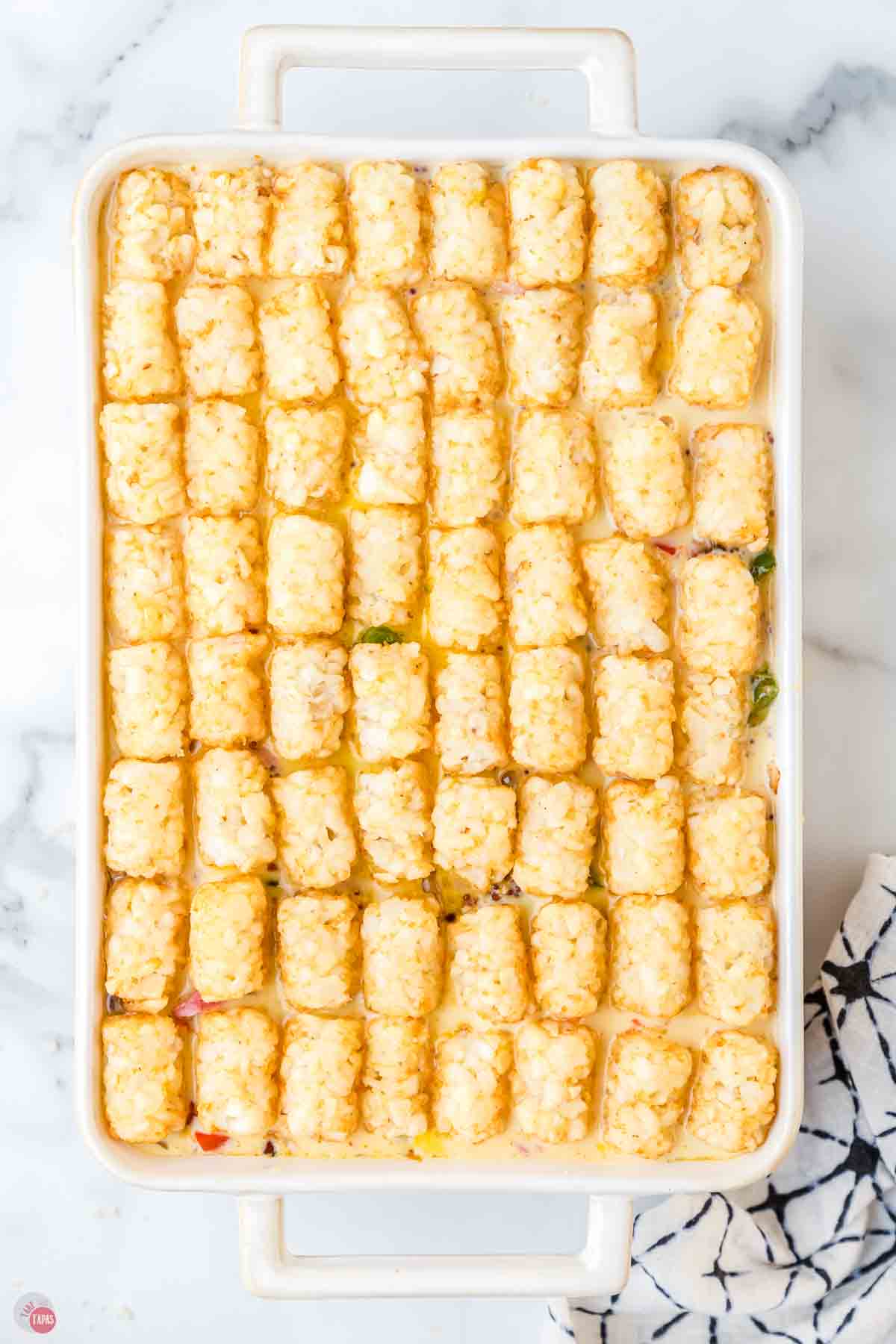 tater tots lined up in a white casserole dish