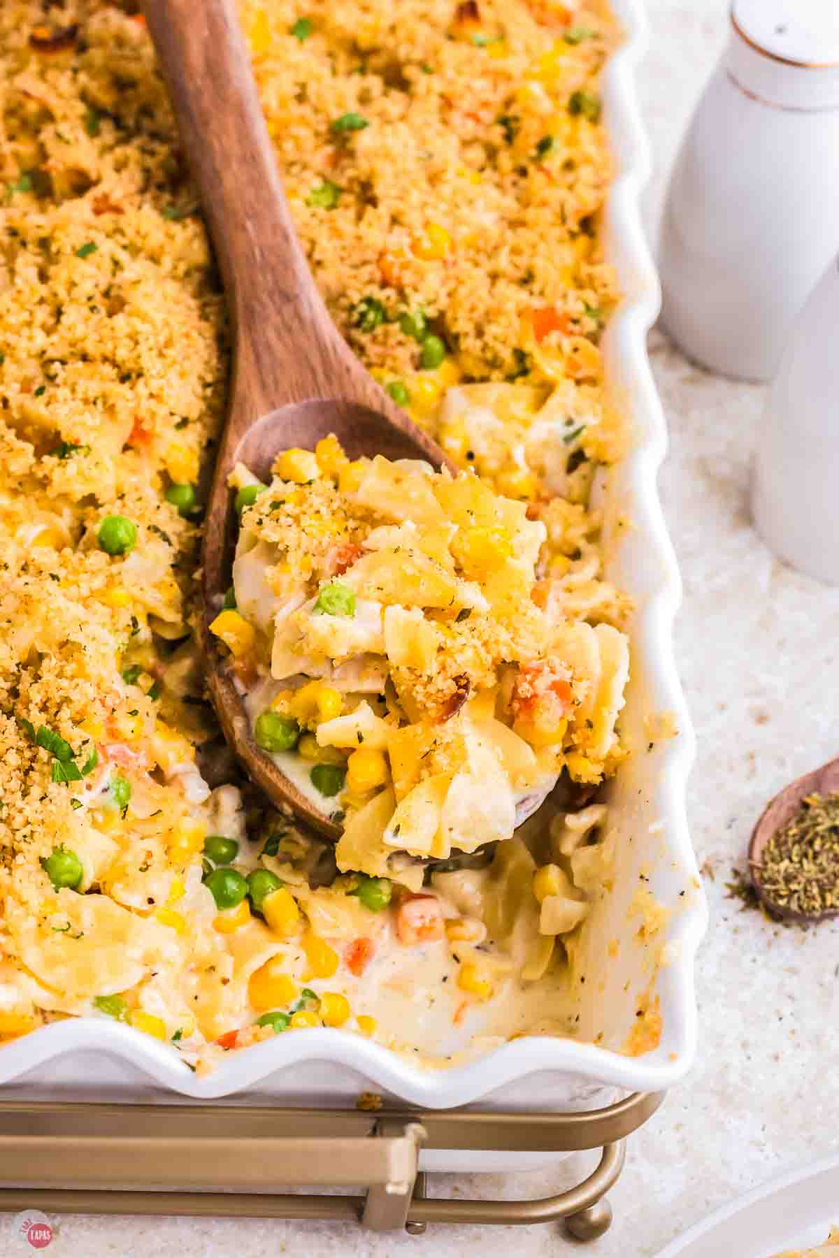 creamy chicken casserole in a white dish with a spoon scooping some out