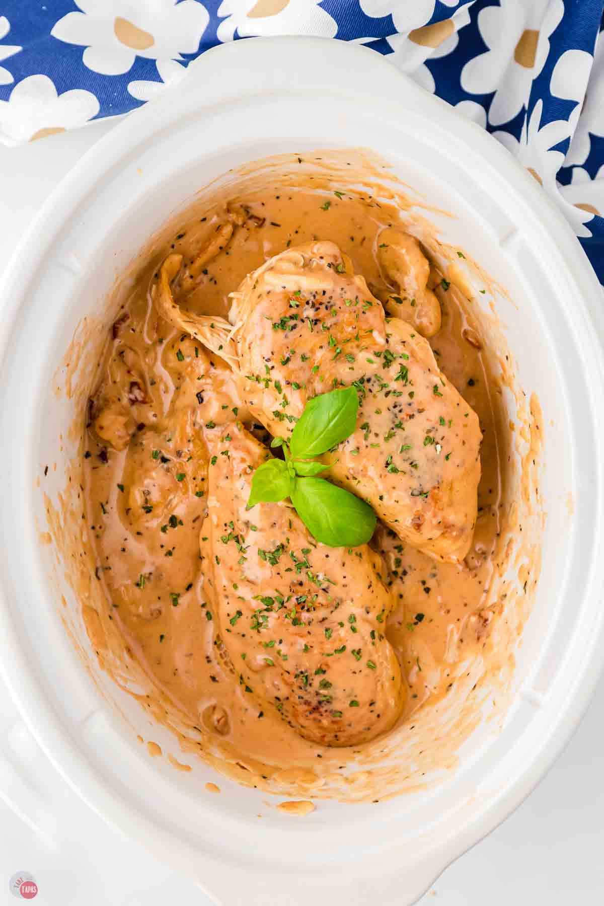 white slow cooker with chicken and cream sauce in it