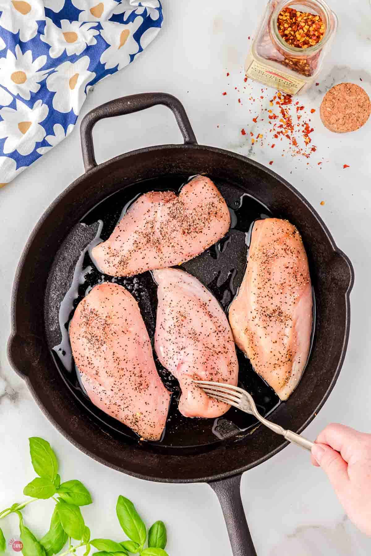 chicken breasts cooking in a black skillet
