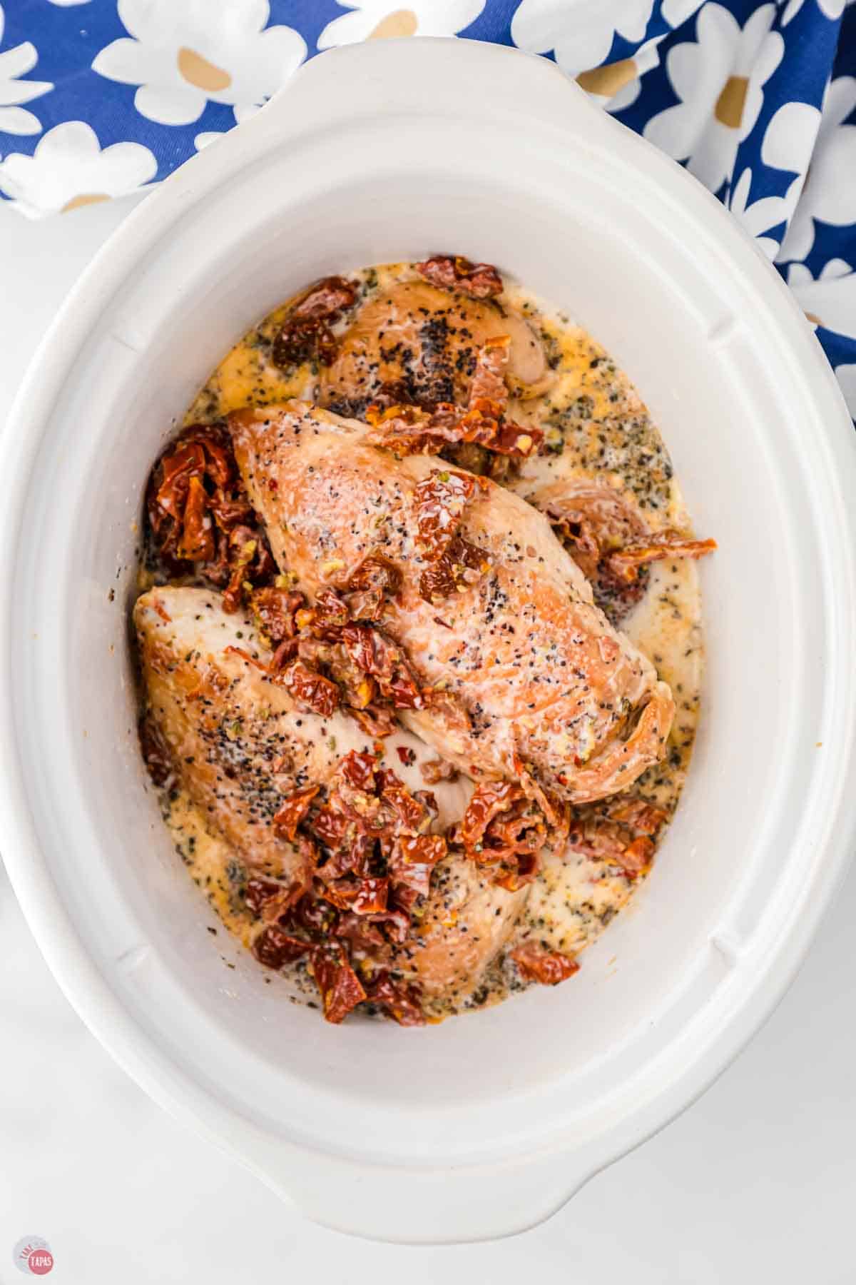 chicken and tomatoes cooking in a white crock pot
