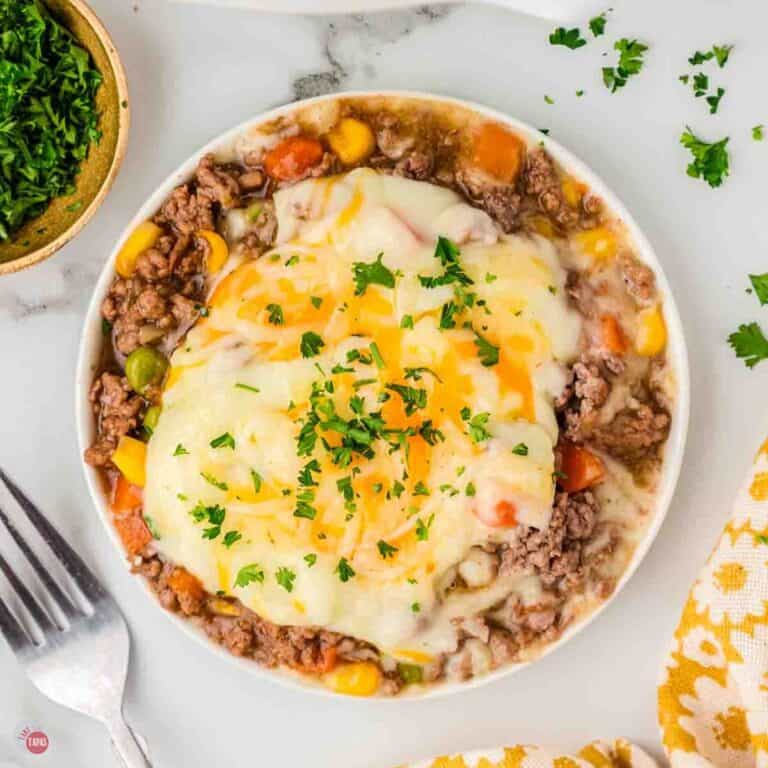 bowl of crockpot shepherds pie with a fork and bowl of parsley next to it