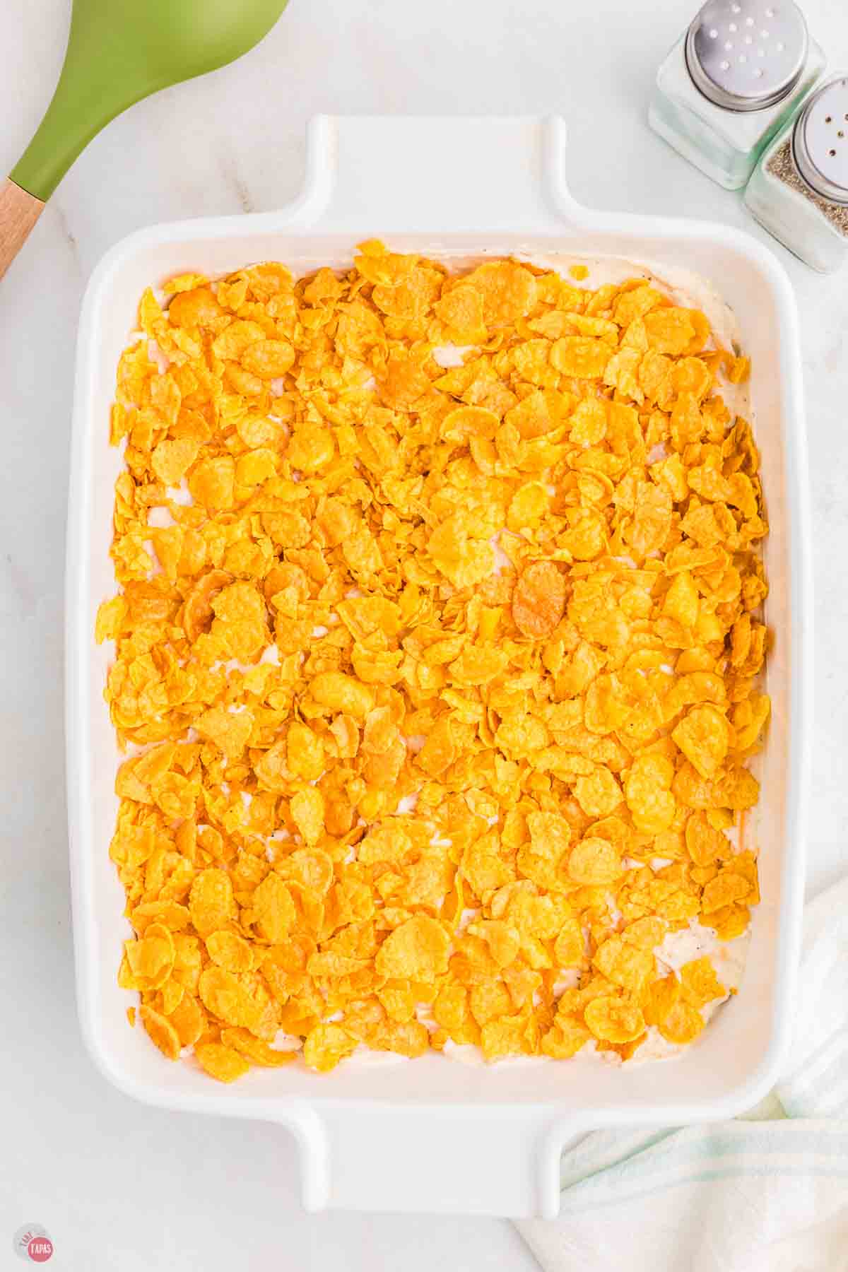 unbaked casserole topped with corn flakes cereal in a white dish