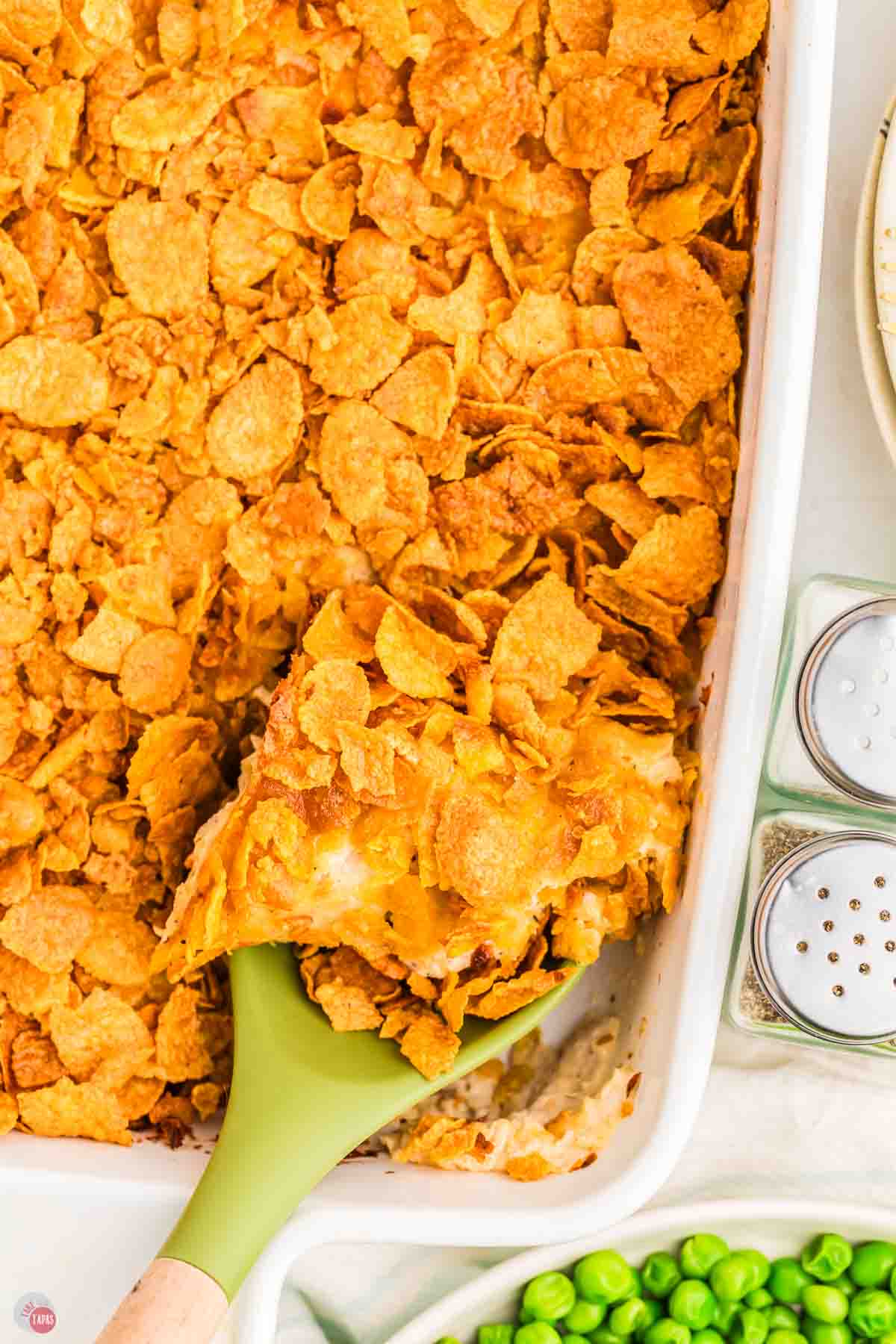 crunchy chicken casserole in a white dish with a green spatula