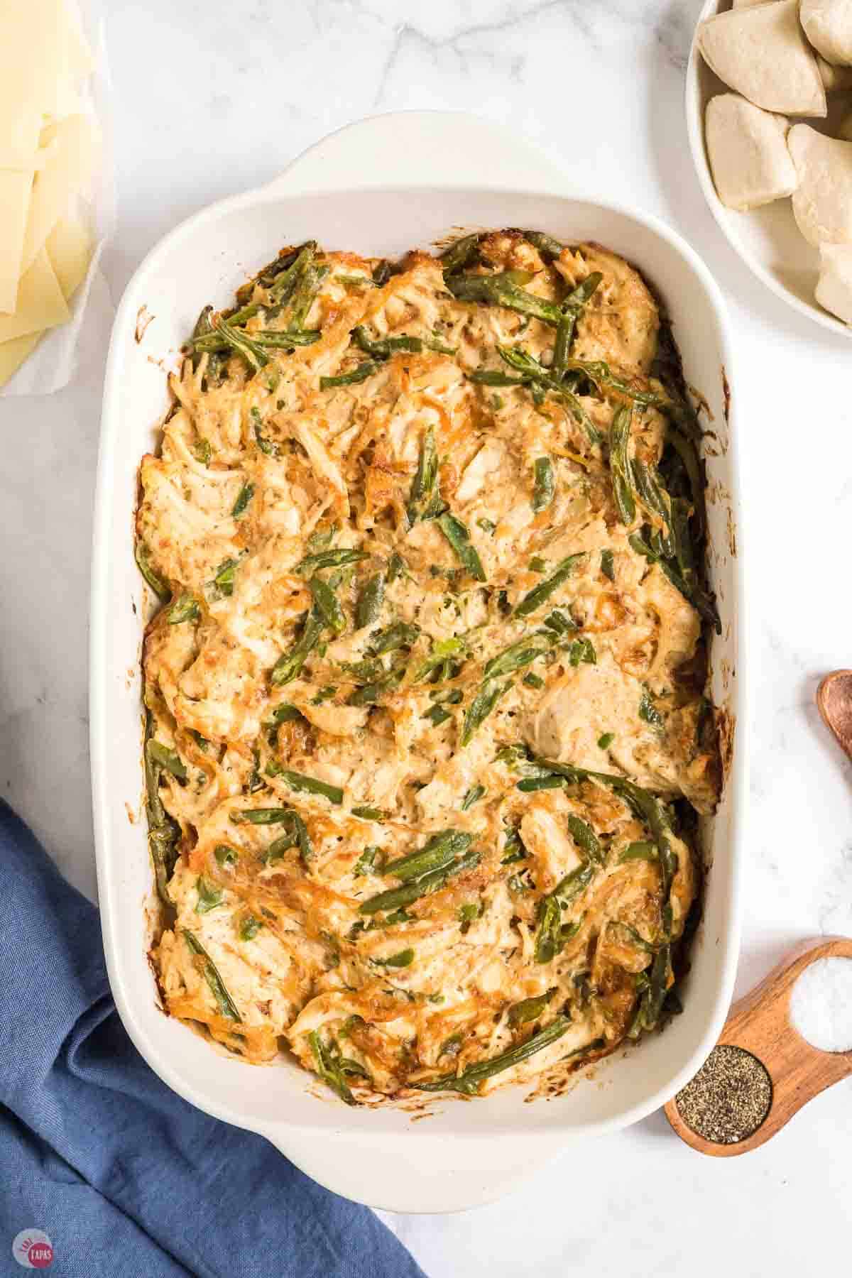 baked chicken and green beans in a white casserole dish