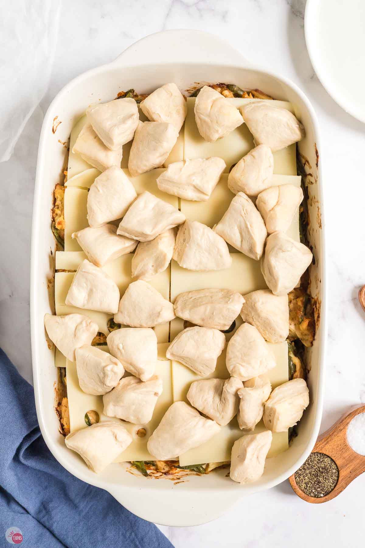 cut biscuits in a white casserole dish with melted butter on top