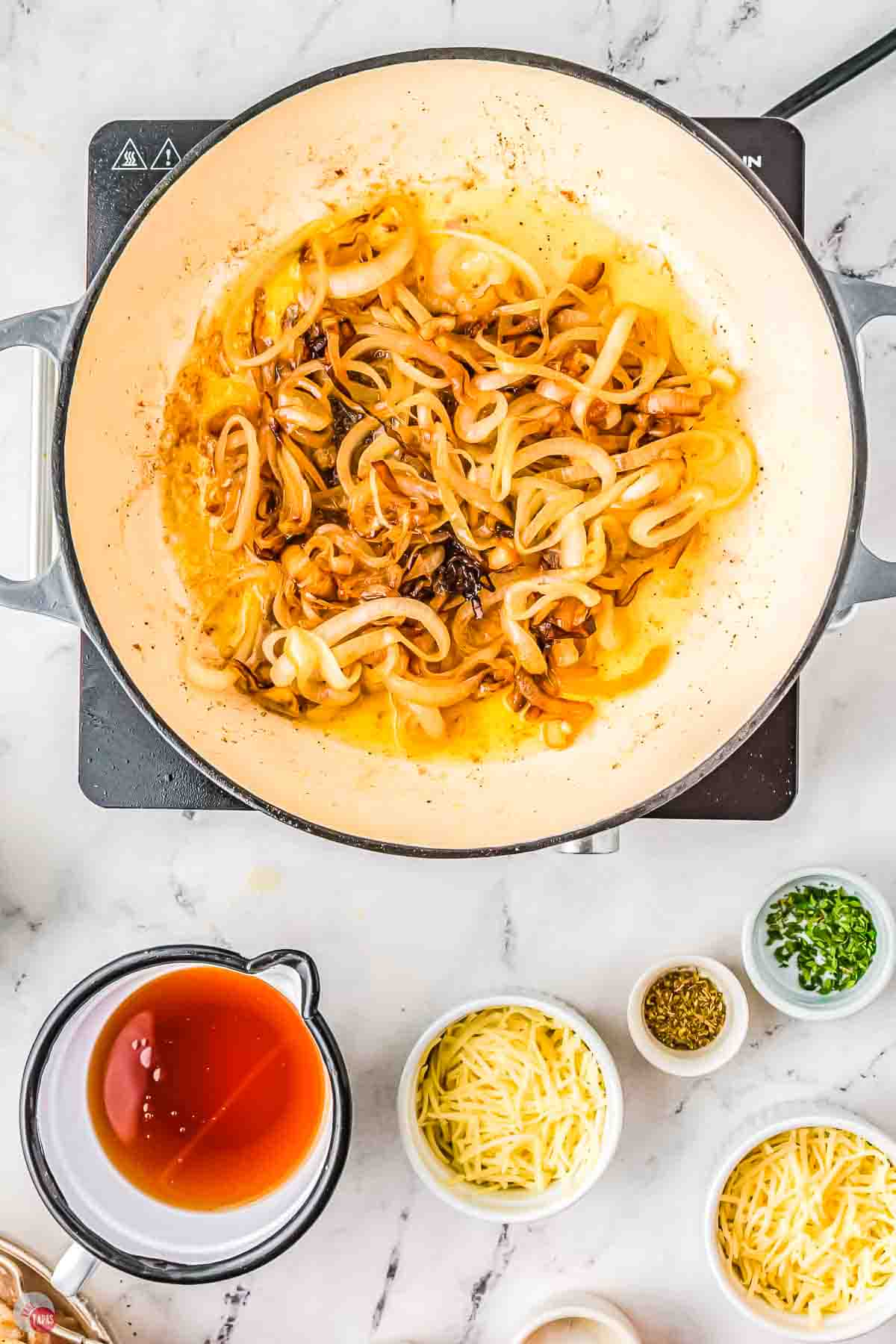 cooked onions in a white pan with small bowls of ingredients next to it