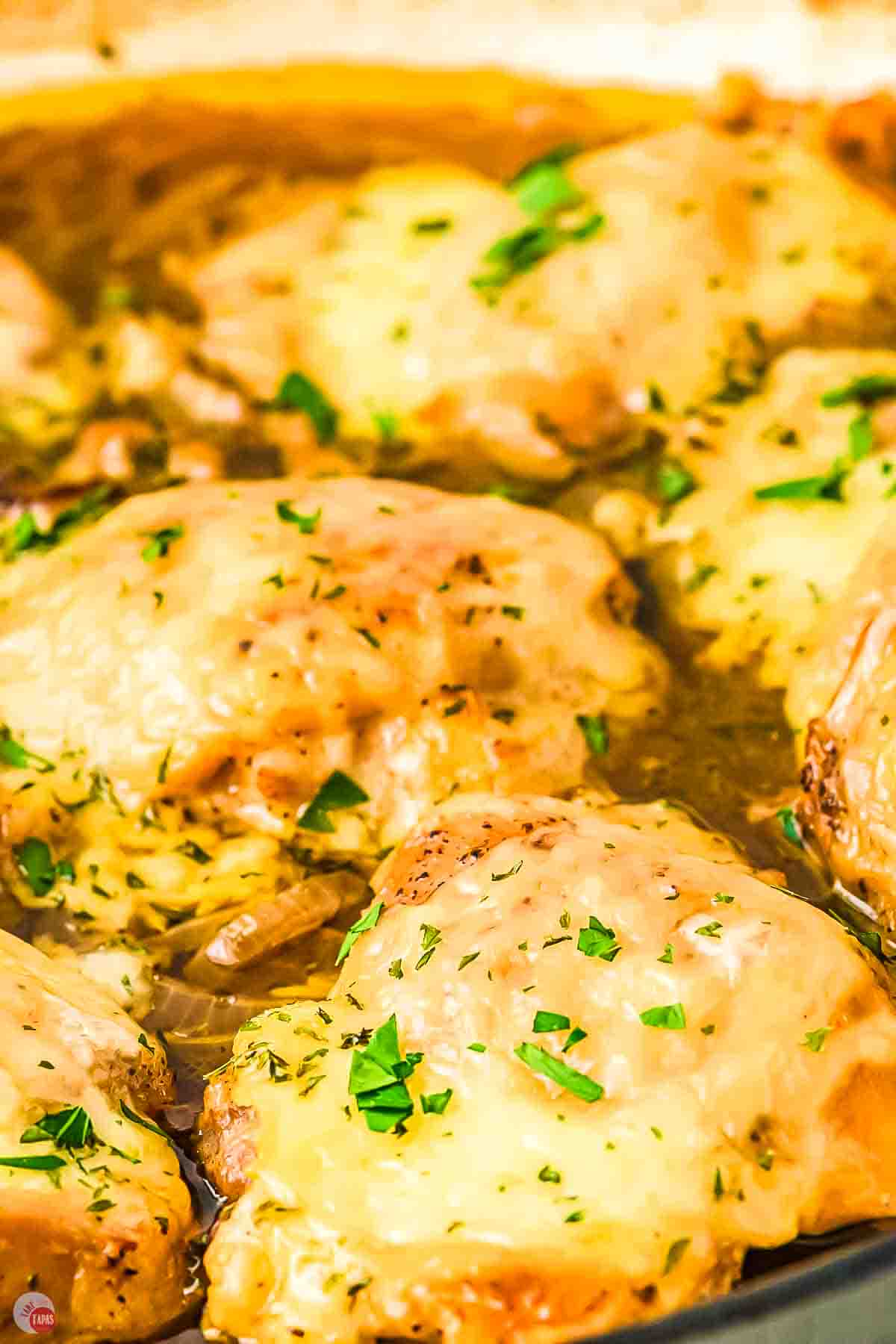 close up of chicken thighs cooking in a sauce