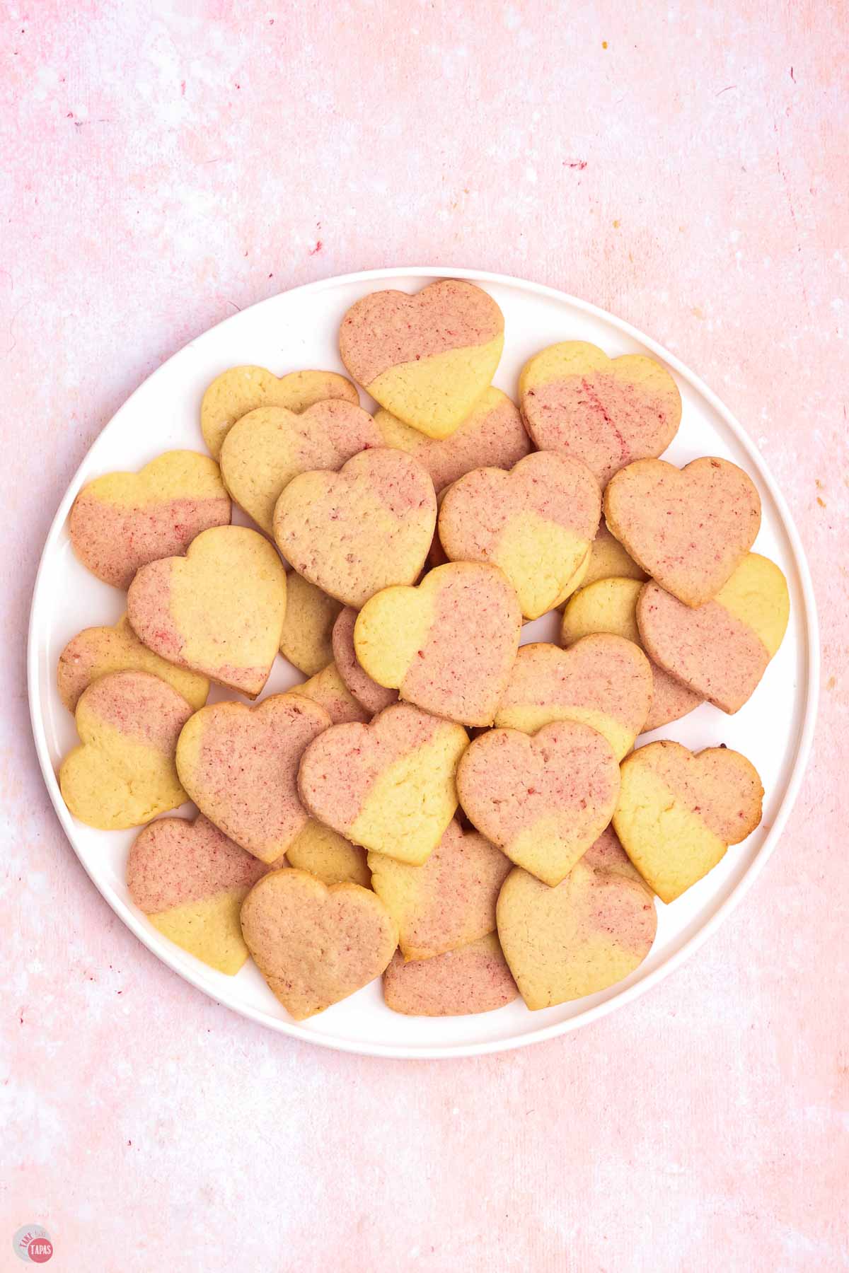 white plate filled with pink sugar cookies in heart shapes