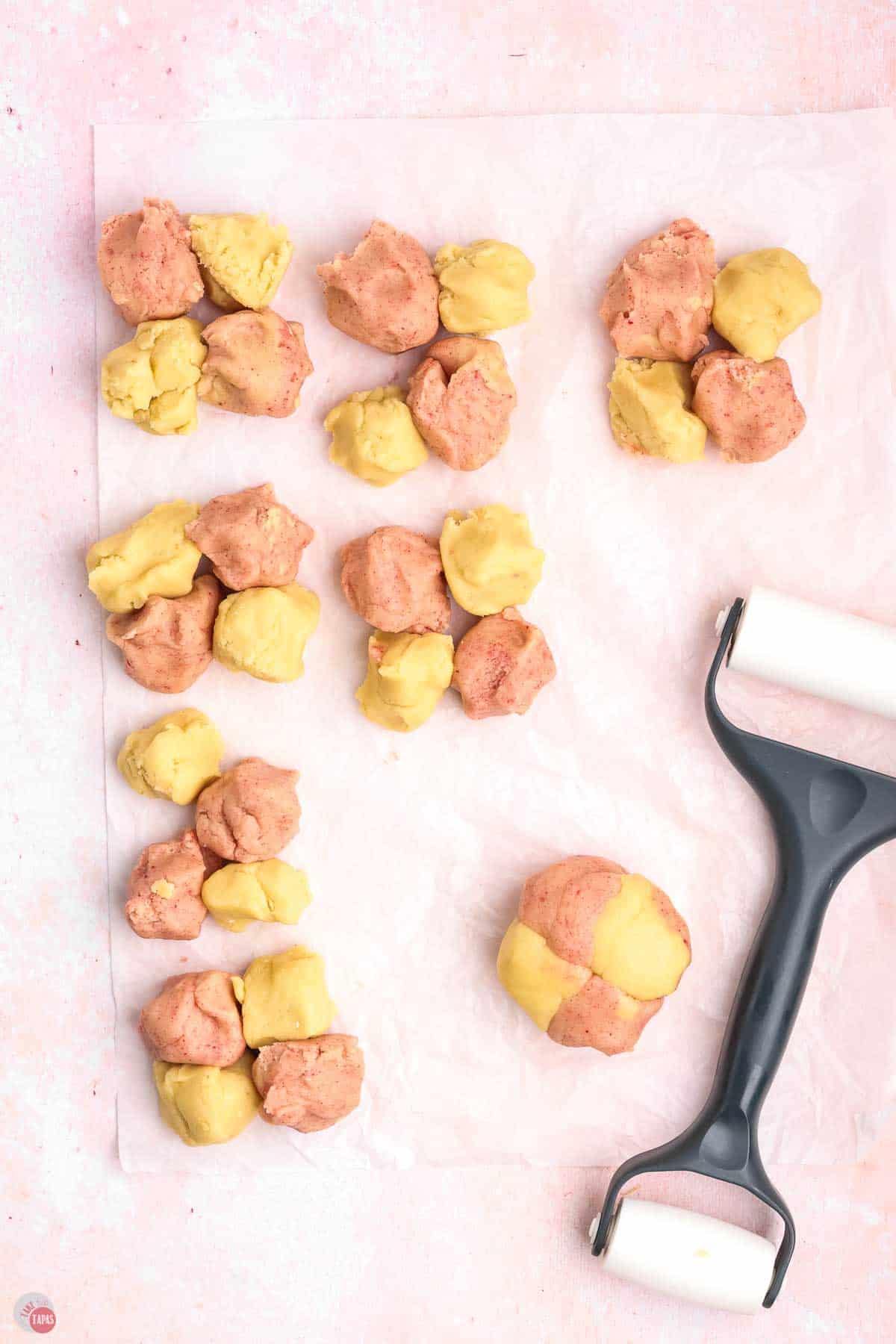 small balls of colored cookie dough on parchment paper