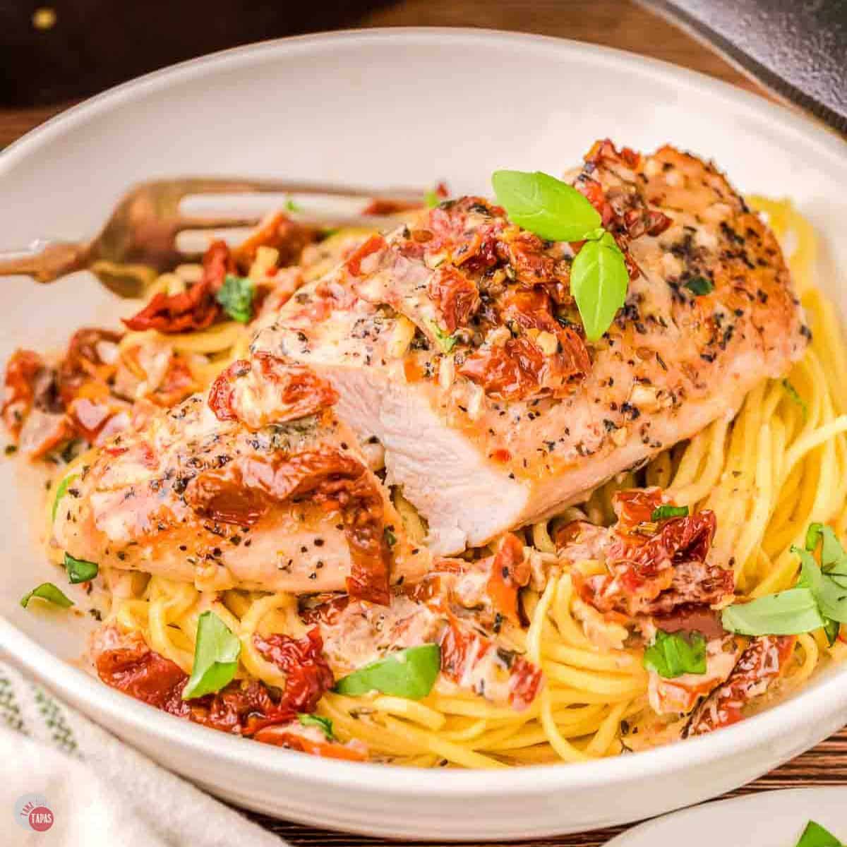 white bowl with pasta topped with a piece of marry me chicken