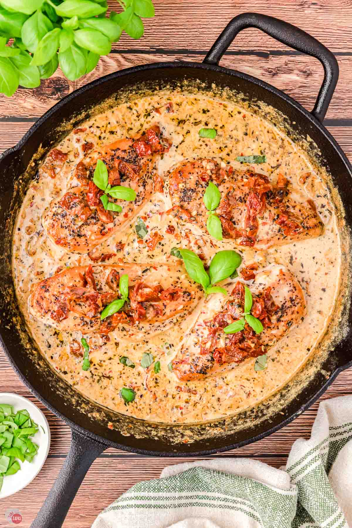 iron skillet with 4 pieces of chicken and cream sauce