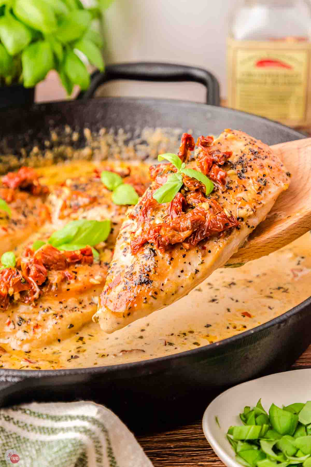 spoon with a piece of chicken over a skillet