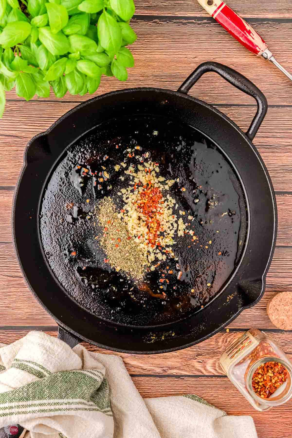 iron skillet with garlic and spices in it
