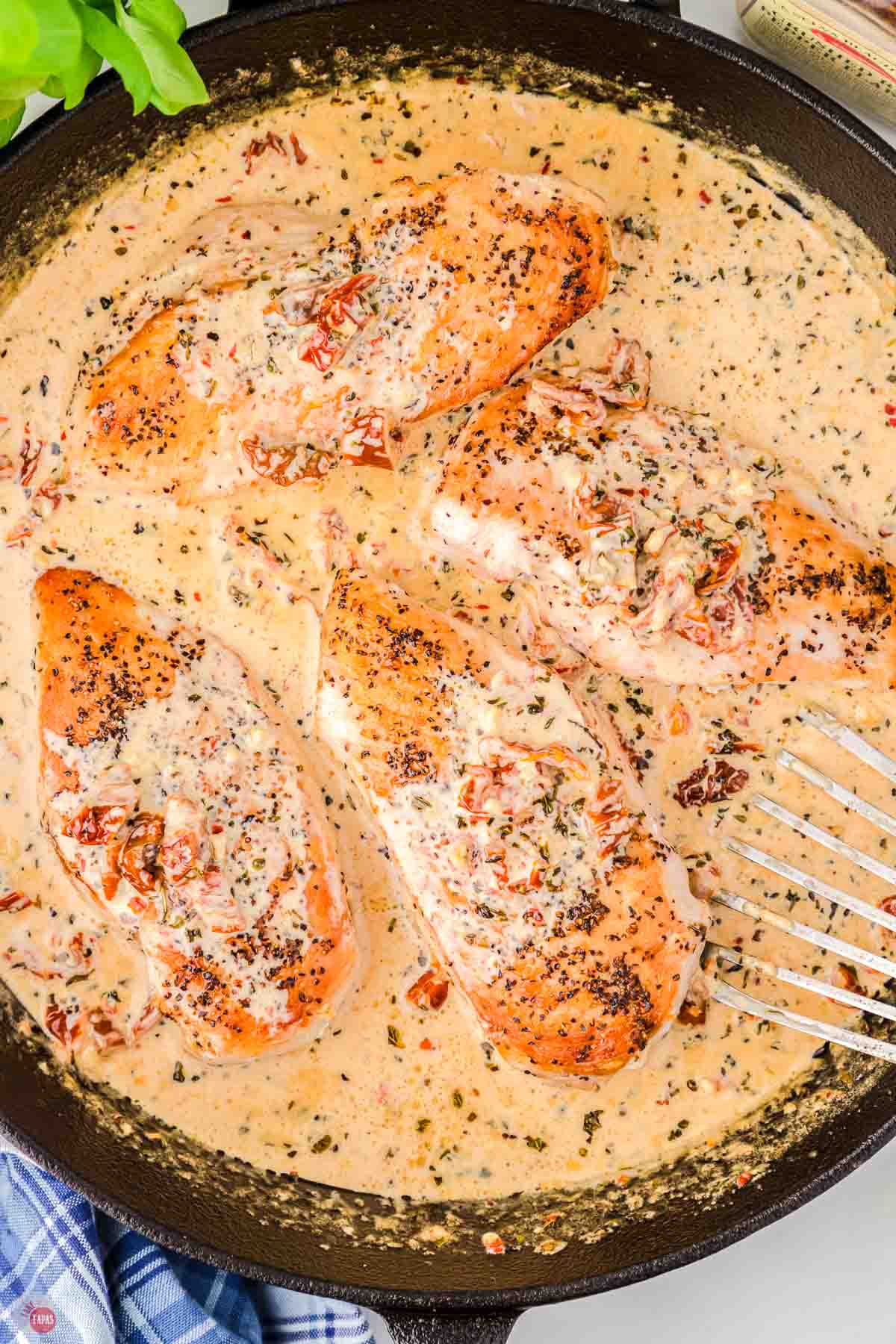 cooked chicken breasts in a skillet with a cream sauce