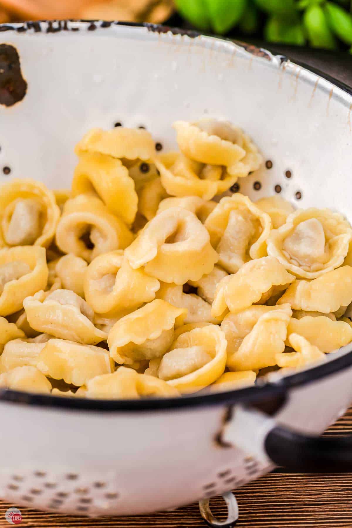 white colander with cooked cheese tortellini in it