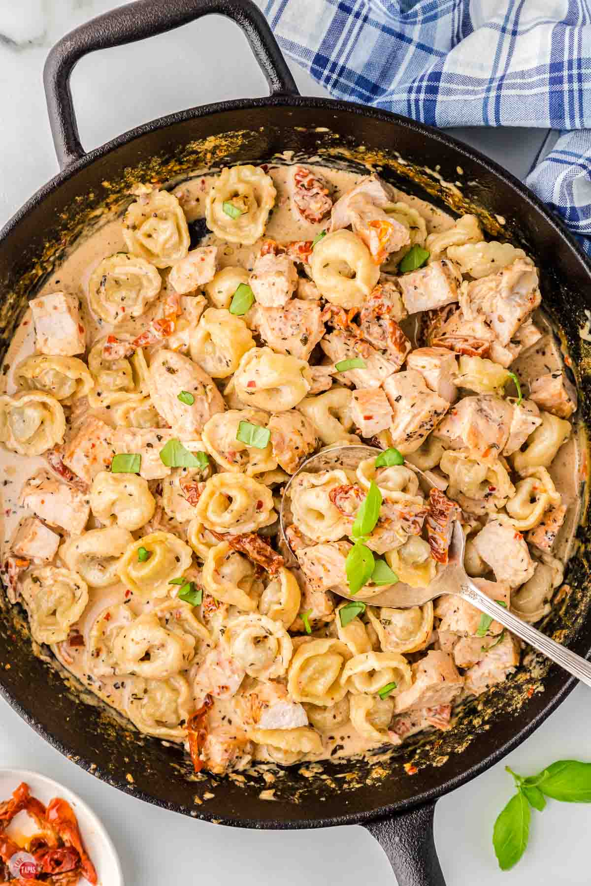 black skillet with chicken, tortellini, and cream sauce in it