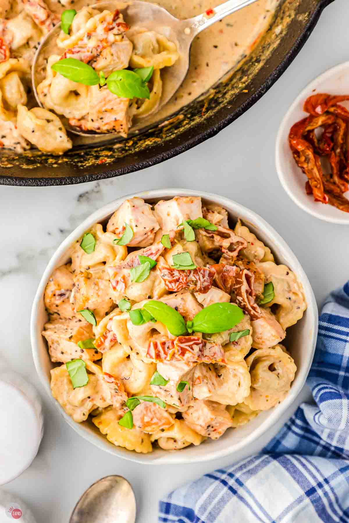 bowl of chicken and pasta next to a skillet