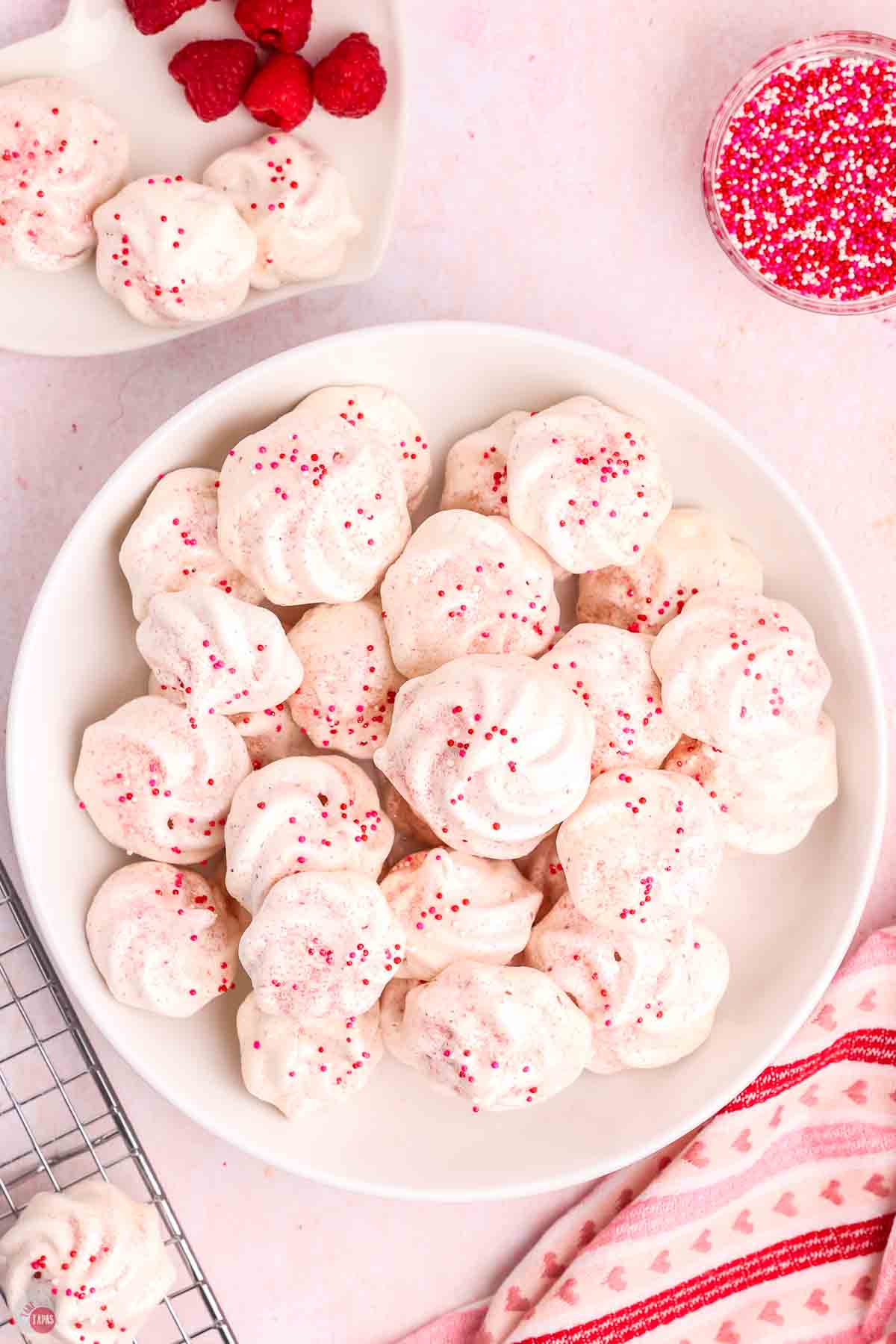 overhead picture of white plate with pink and white meringue cookies on it