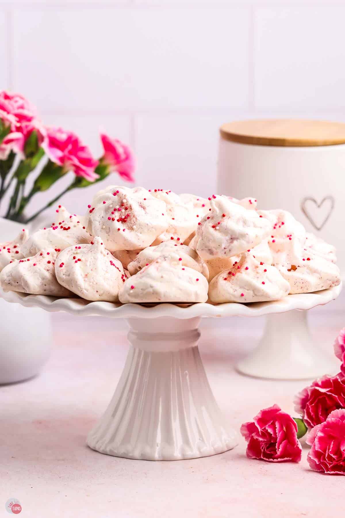 white cake stand with pink meringue cookies on it