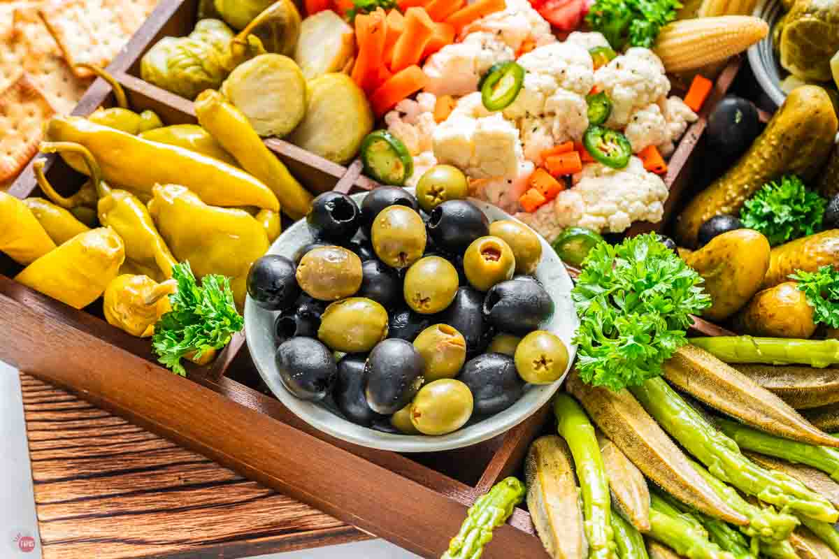 close up of olives and pickled vegetables on a tray