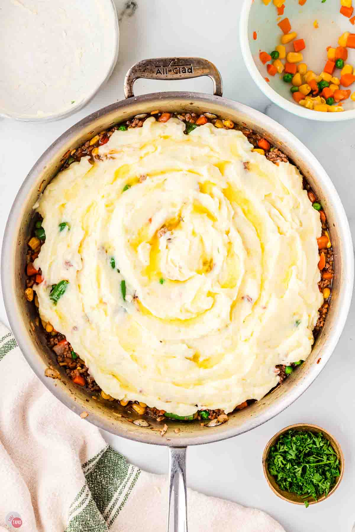 silver skillet filled with ground beef and topped with mashed potatoes and melted butter