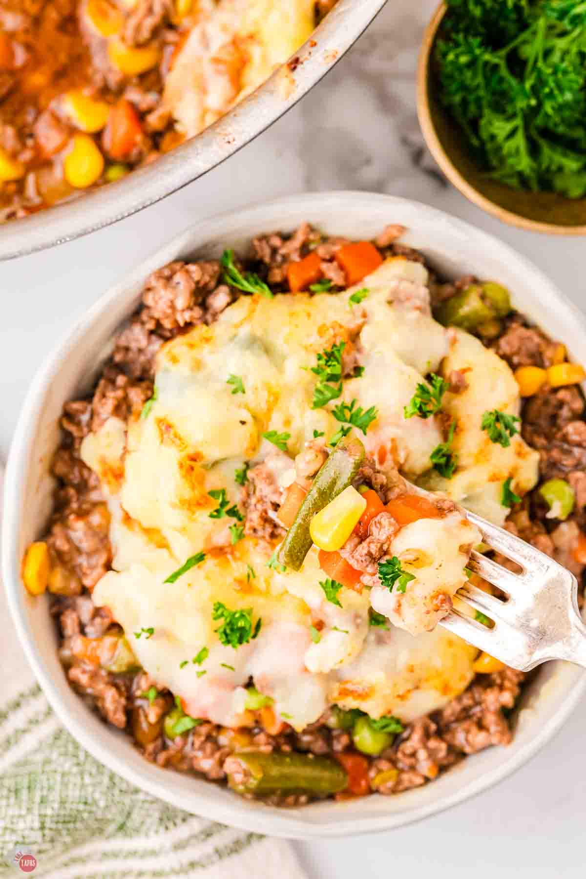 bowl of cottage pie with a fork taking out a bite