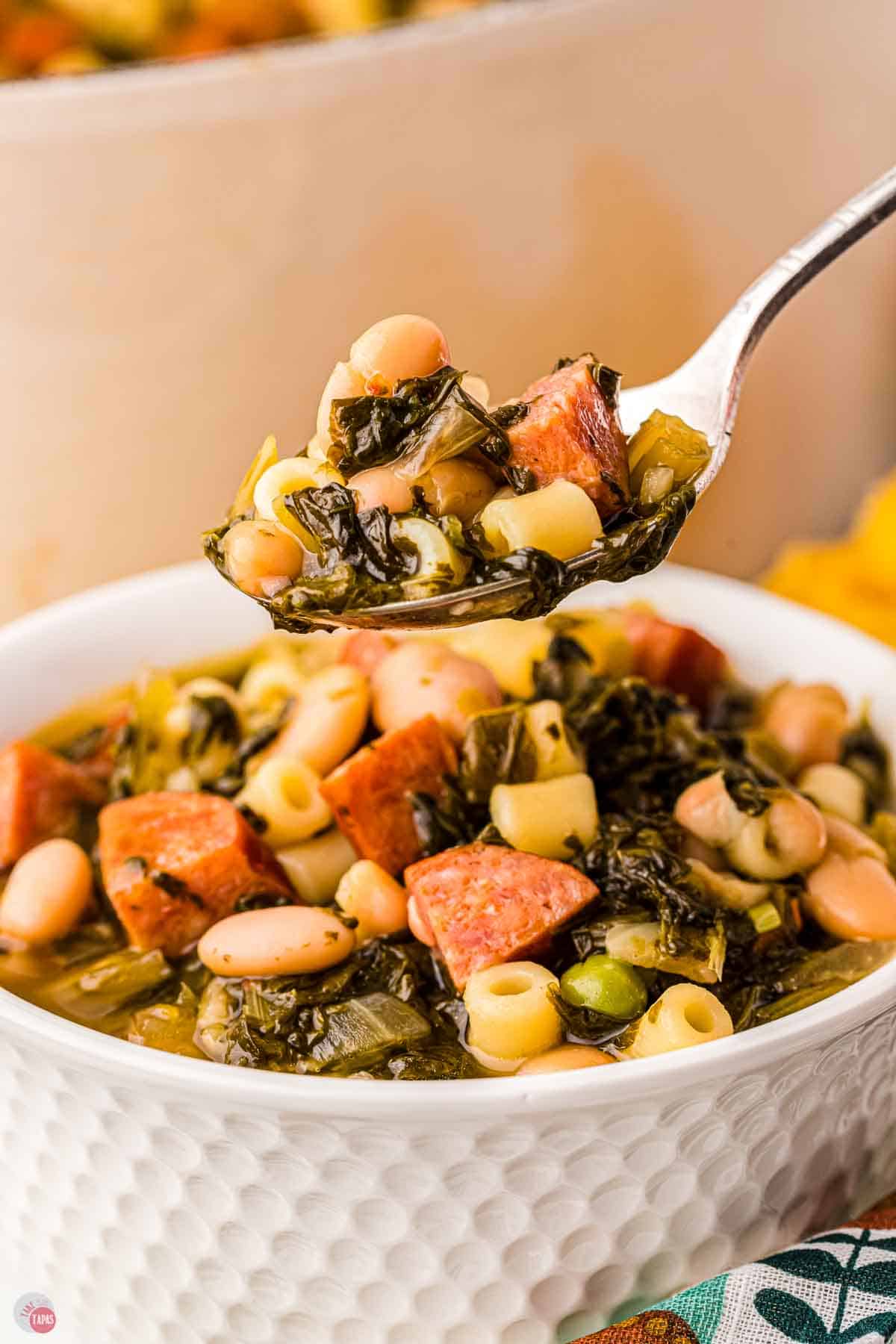 close up of spoon of greens, beans, and sausage